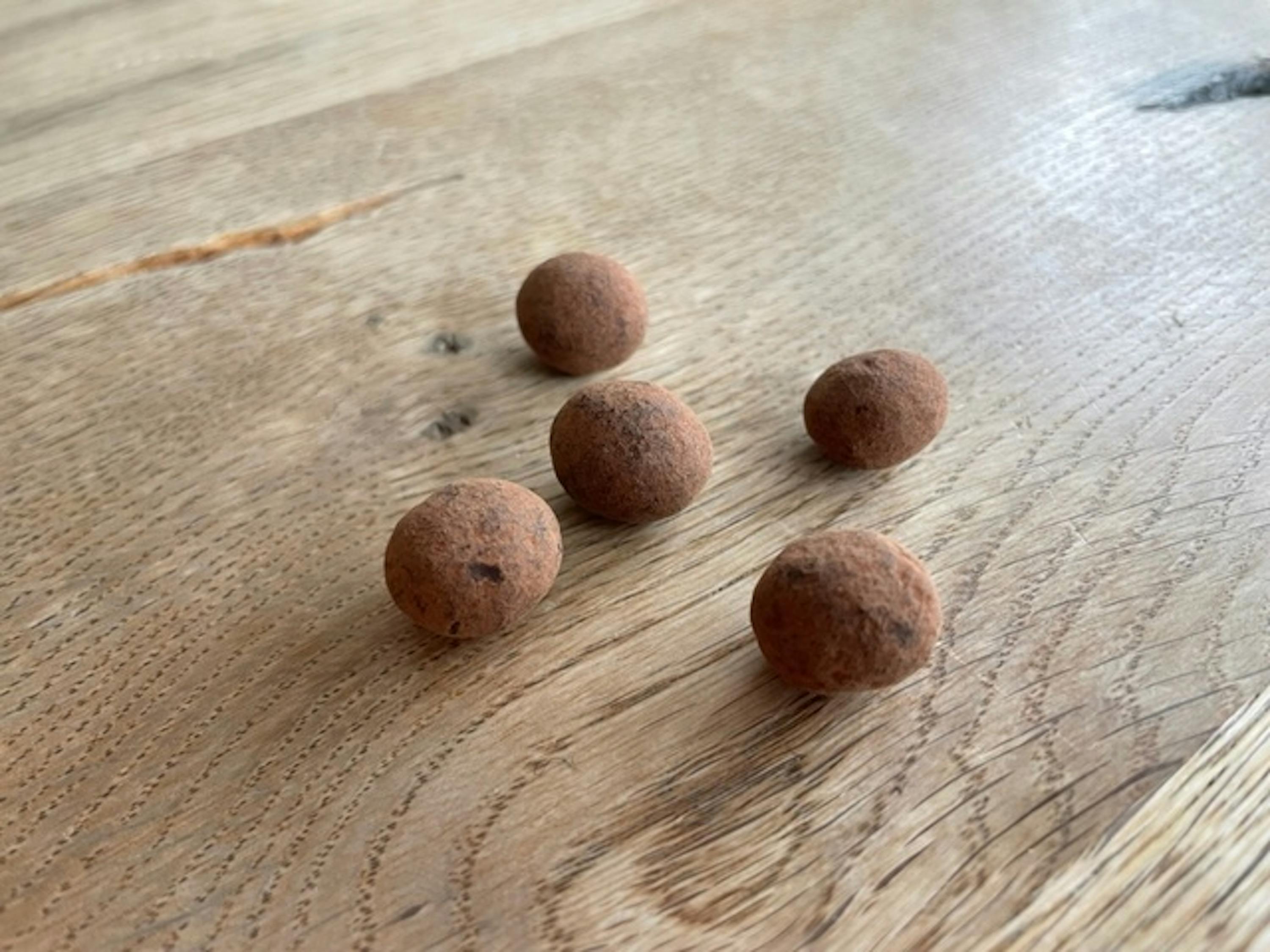 vier Schokoladenkugeln liegen auf einem Holztisch