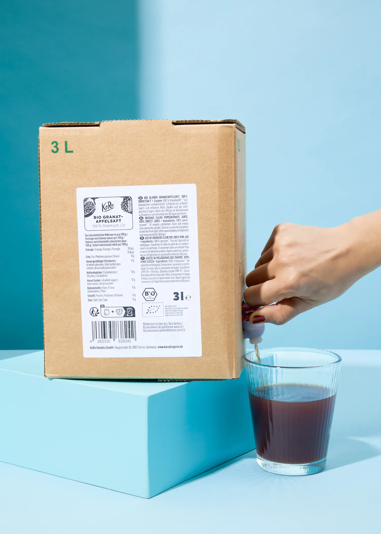 eine Person füllt ein Glas mit einem 3l-Karton