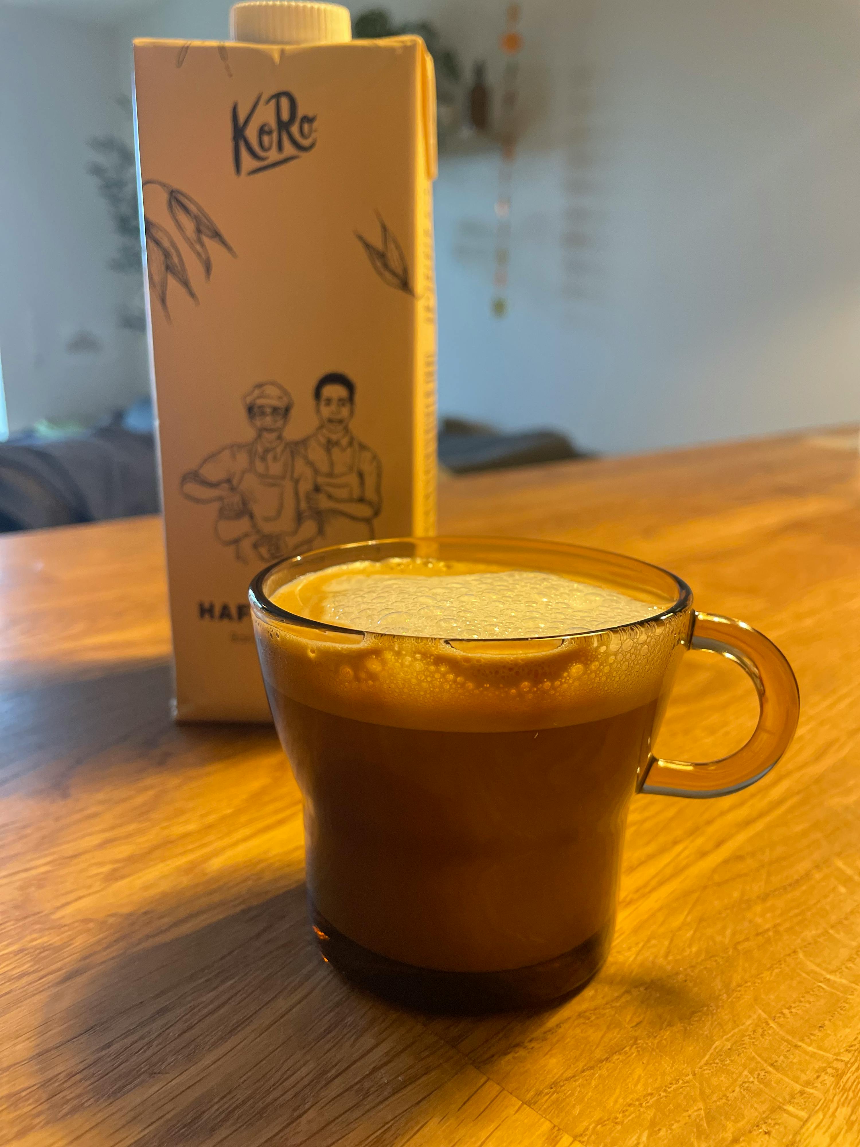 a cup of coffee sits next to a carton of karo milk