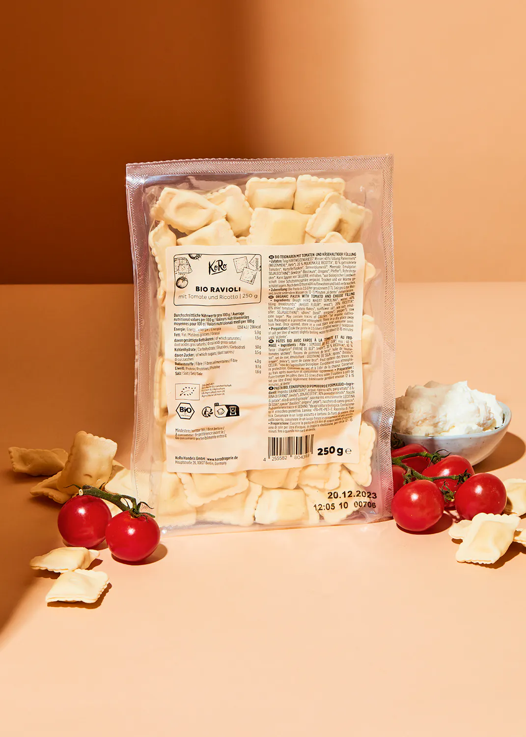 a bag of ravioli sits on a table with tomatoes and cheese