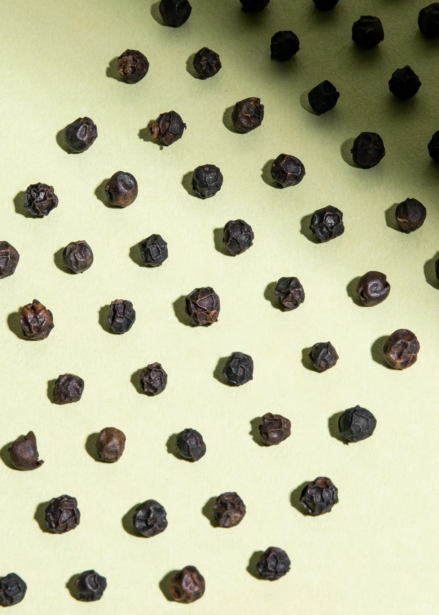 un tas de poivrons noirs posés sur une surface verte