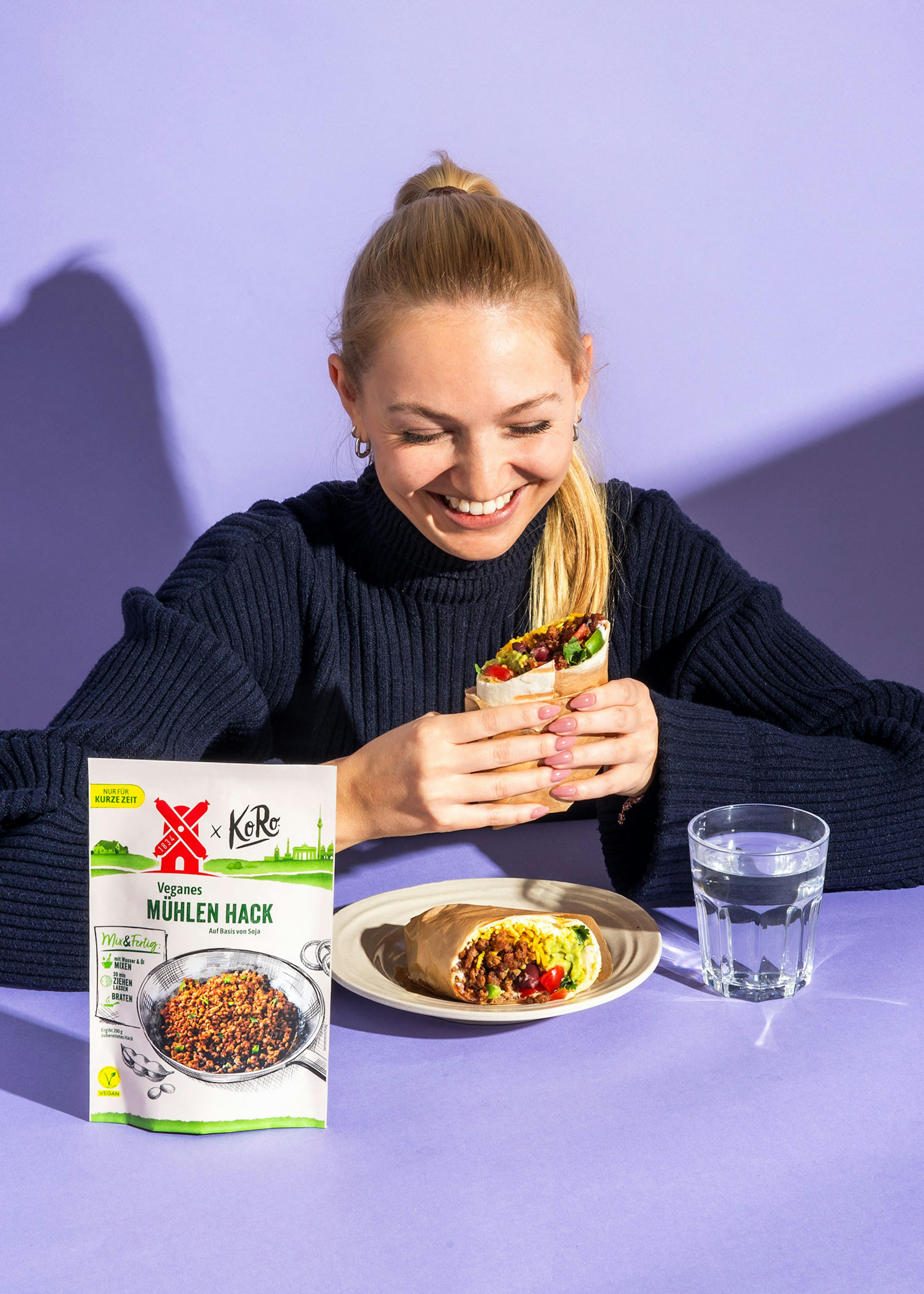 eine frau isst einen burrito neben einem paket von koko