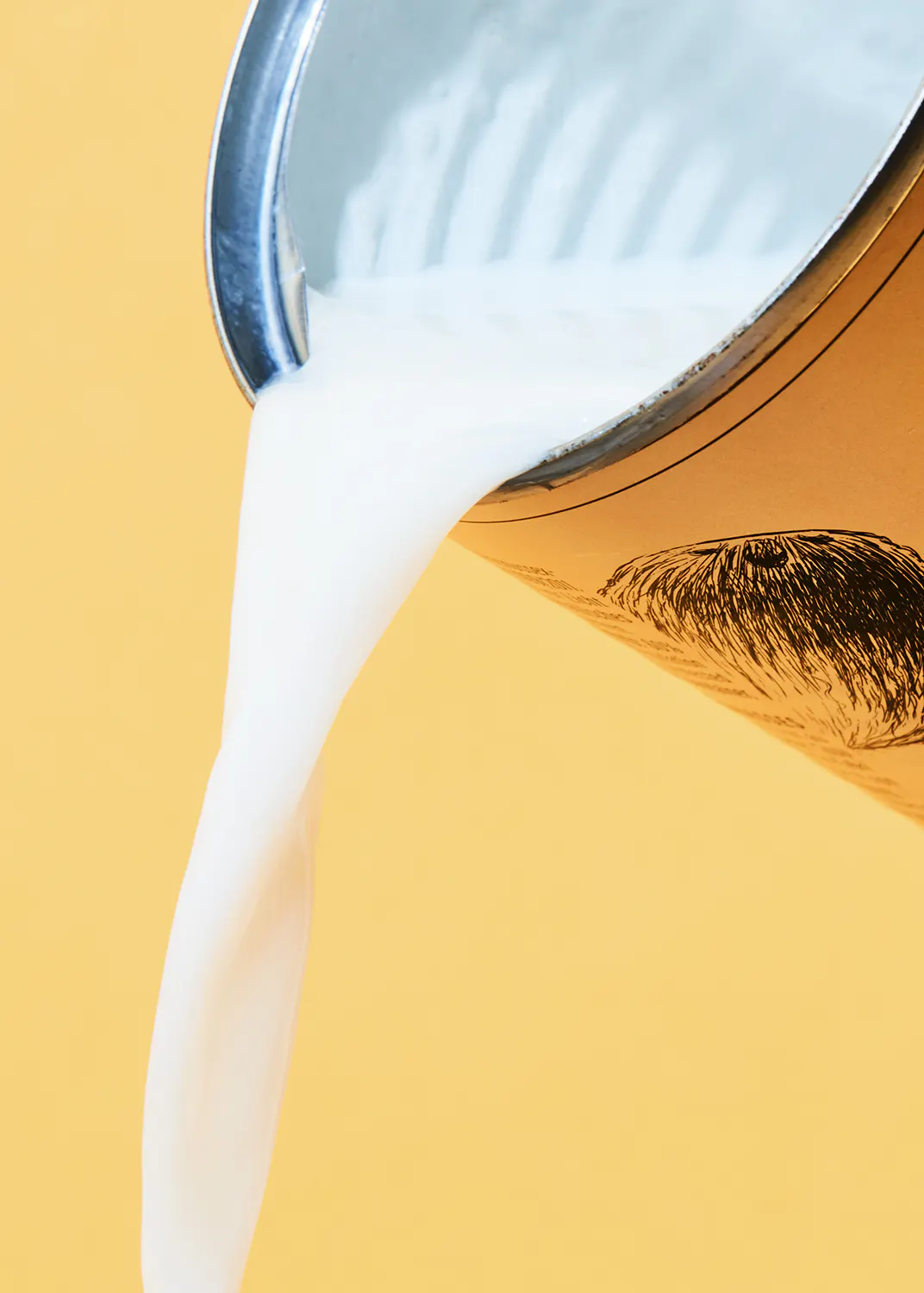 du lait est versé d' un seau sur fond jaune