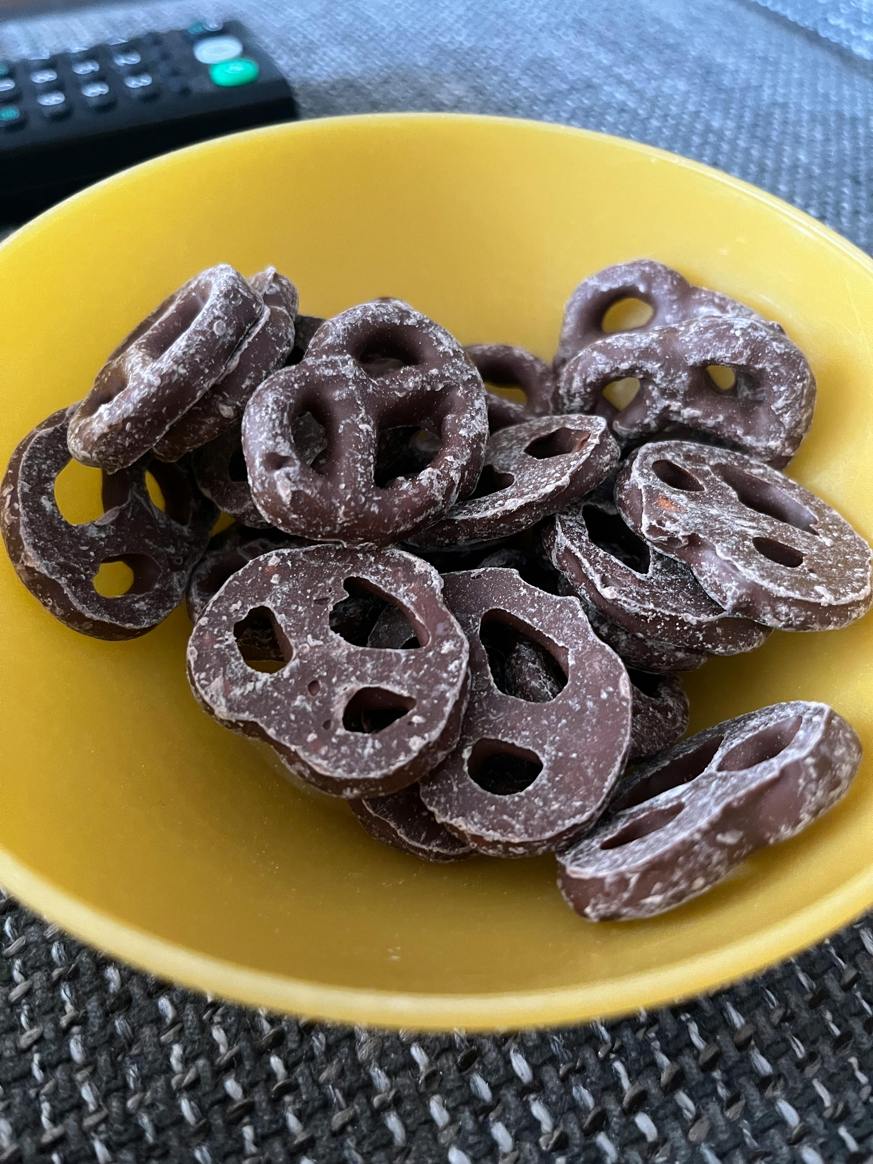 ein gelber Teller mit schokoladenförmigen Brezeln auf einem Tisch