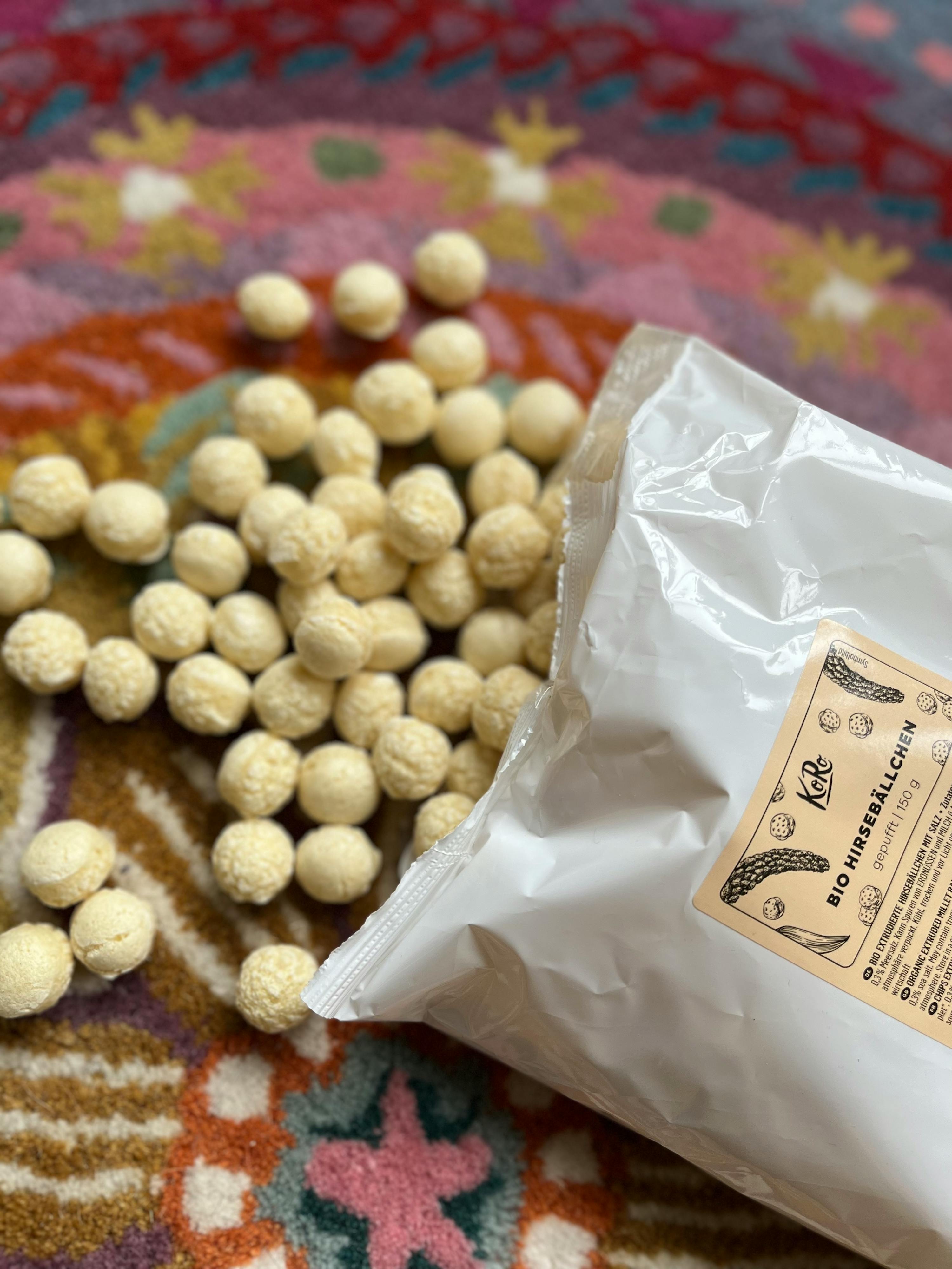 eine Tüte bio hirsballchen liegt auf einem Teppich