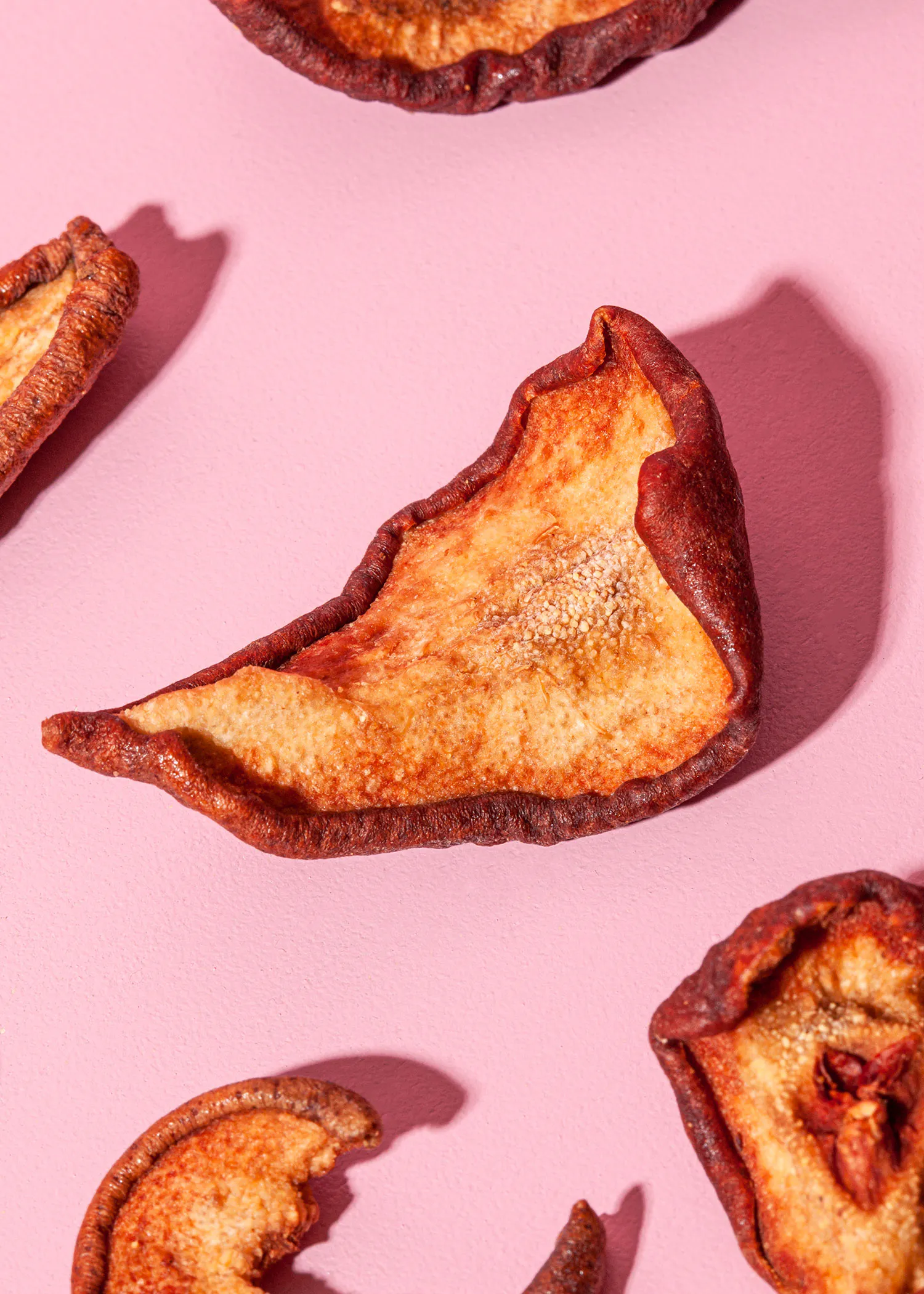 un gros plan d' une poire séchée sur fond rose