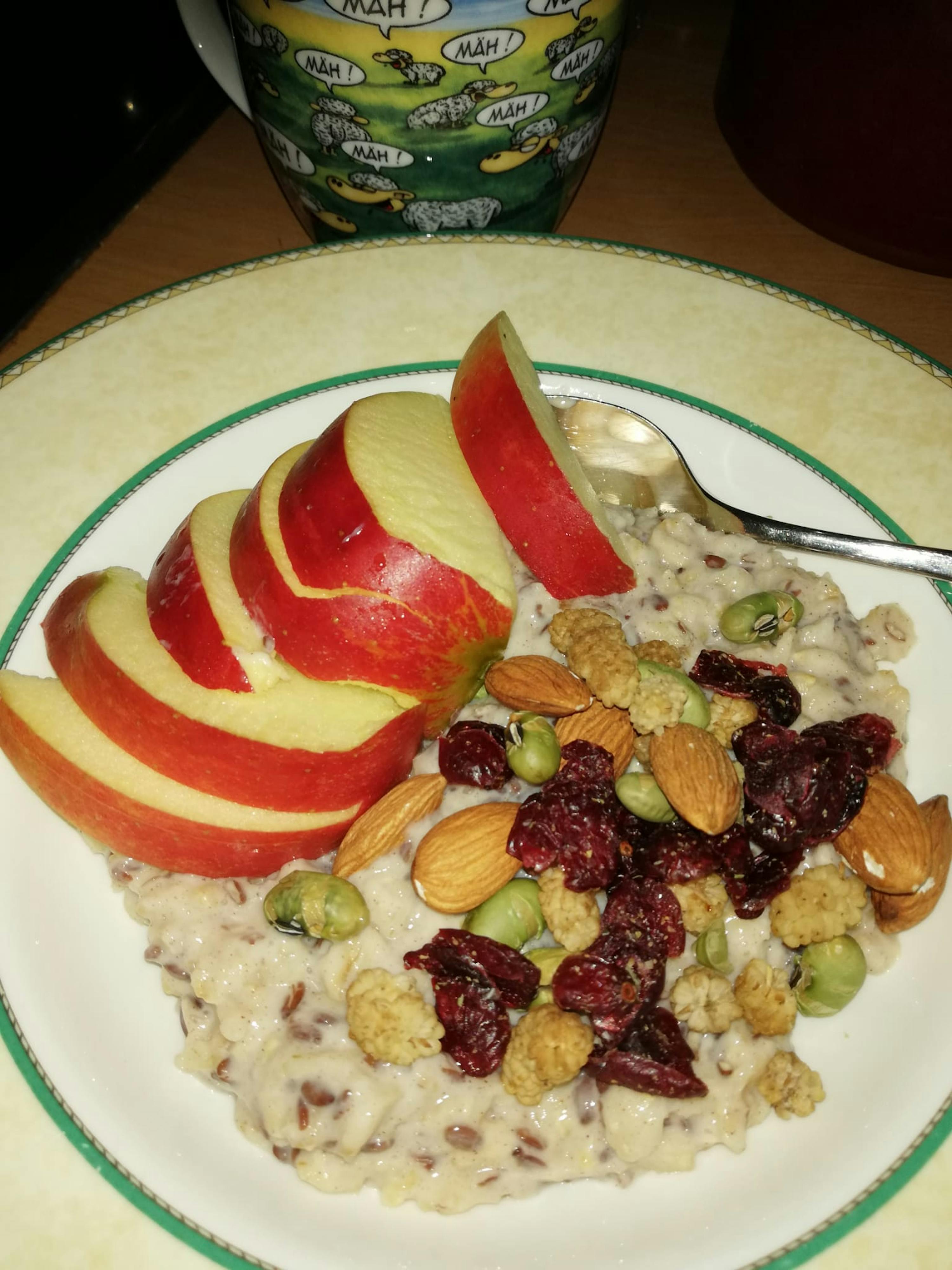 a plate of food with apples and nuts and a mug that says mah on it