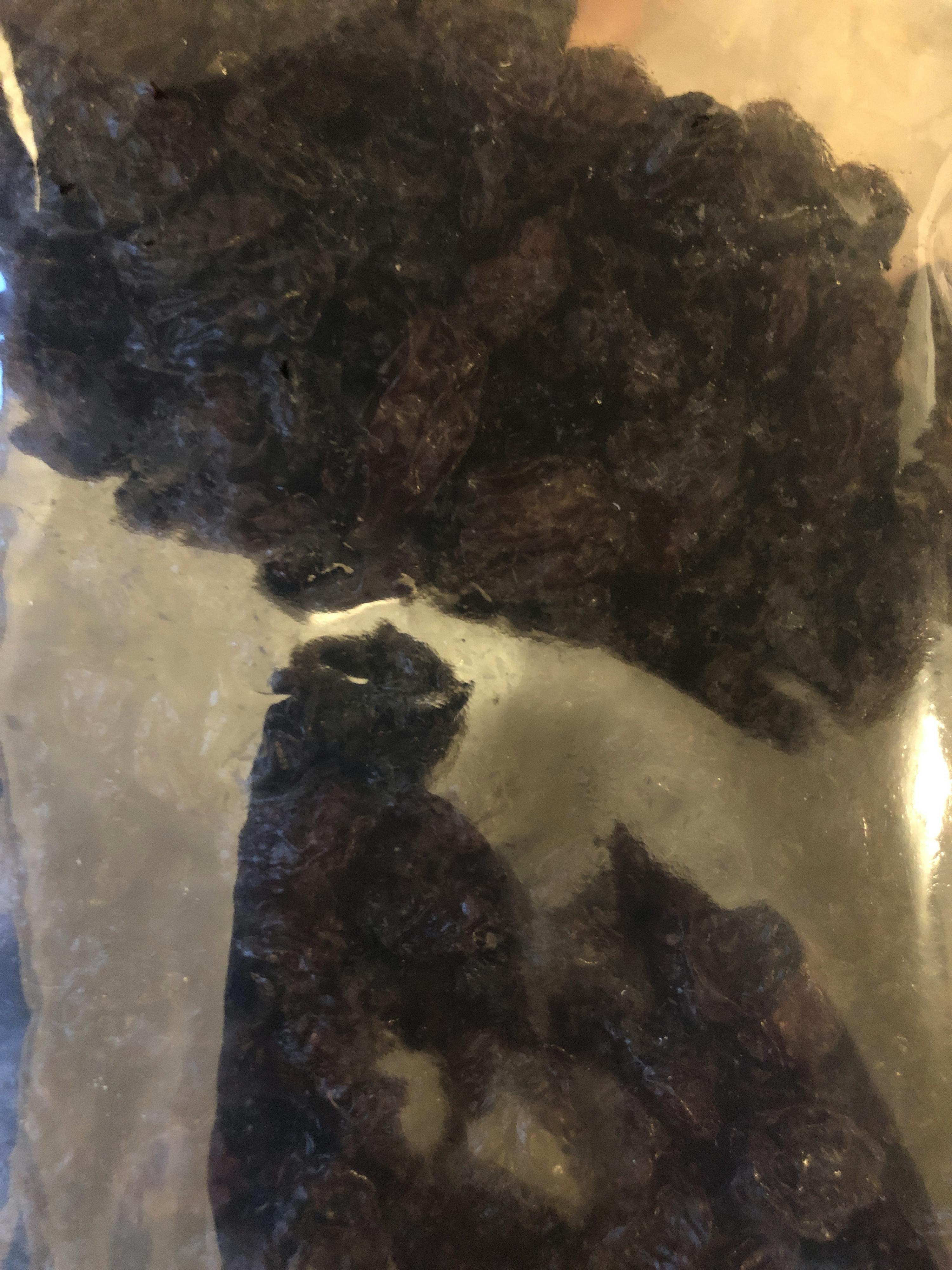 eine Nahaufnahme eines Plastikbeutels mit schwarzen Kirschen