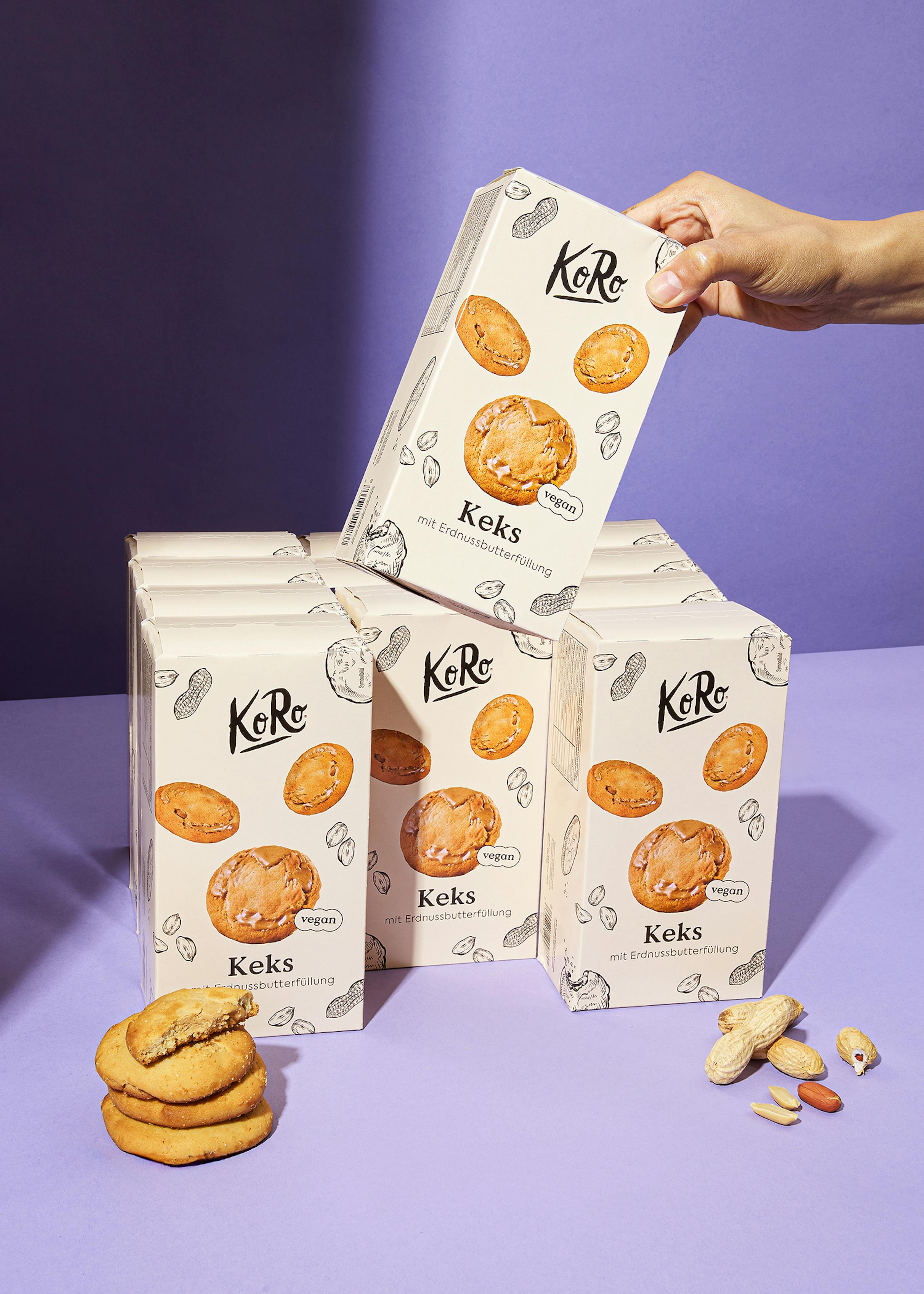 una persona tiene in mano una scatola di keks su un tavolo viola