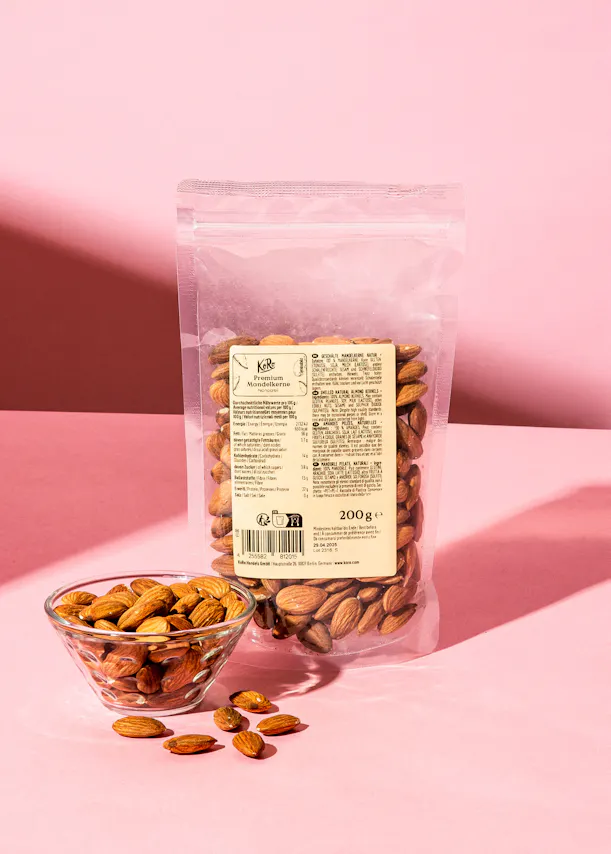 eine Tüte Mandeln steht neben einer Glasschüssel mit Mandeln