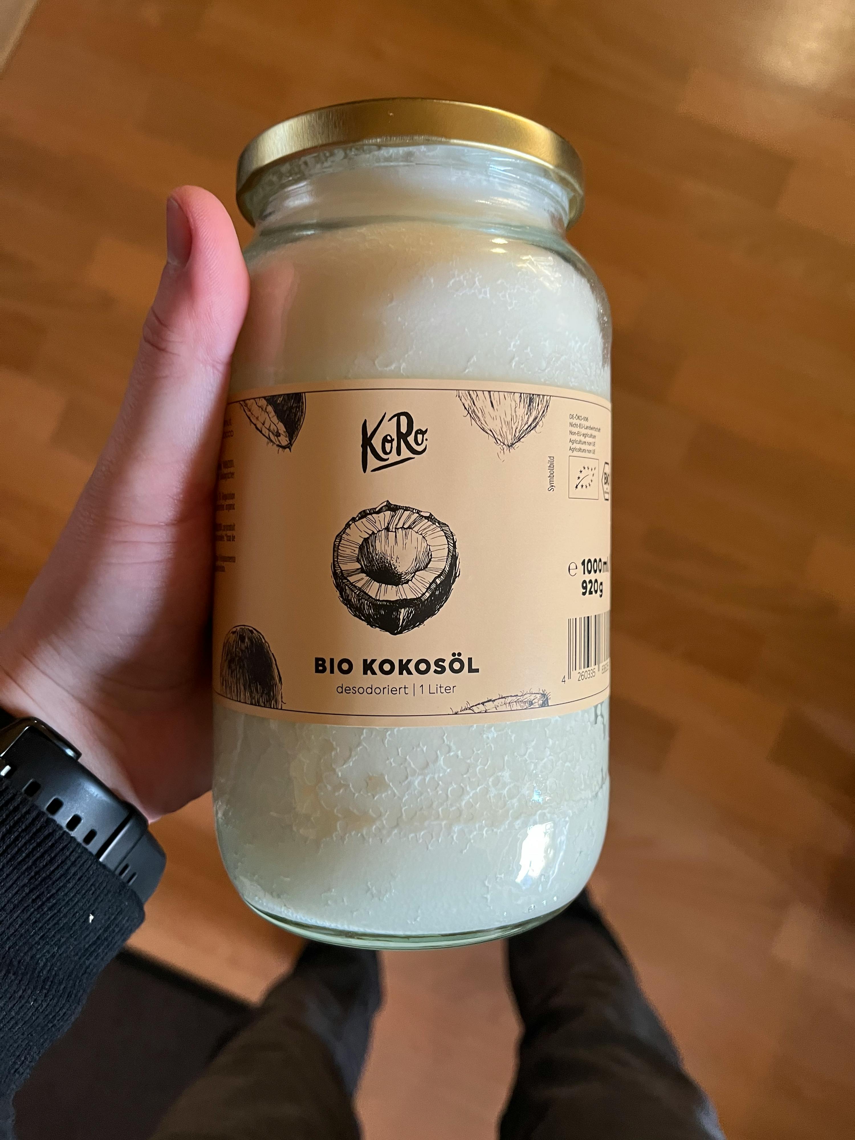 a person holds a jar of bio kokosöl in their hand