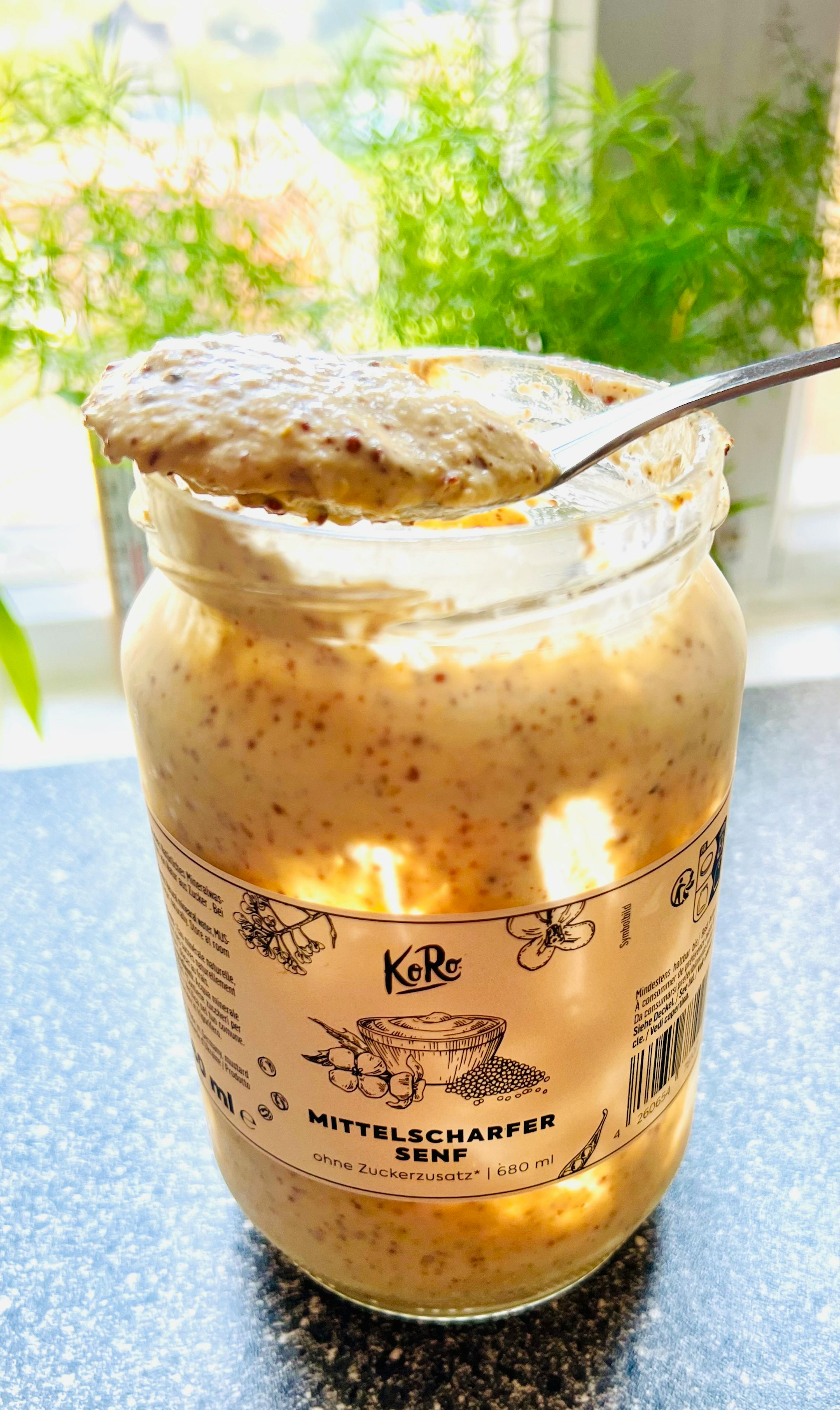 un gros plan d' un bocal de sauce avec une cuillère à l' intérieur