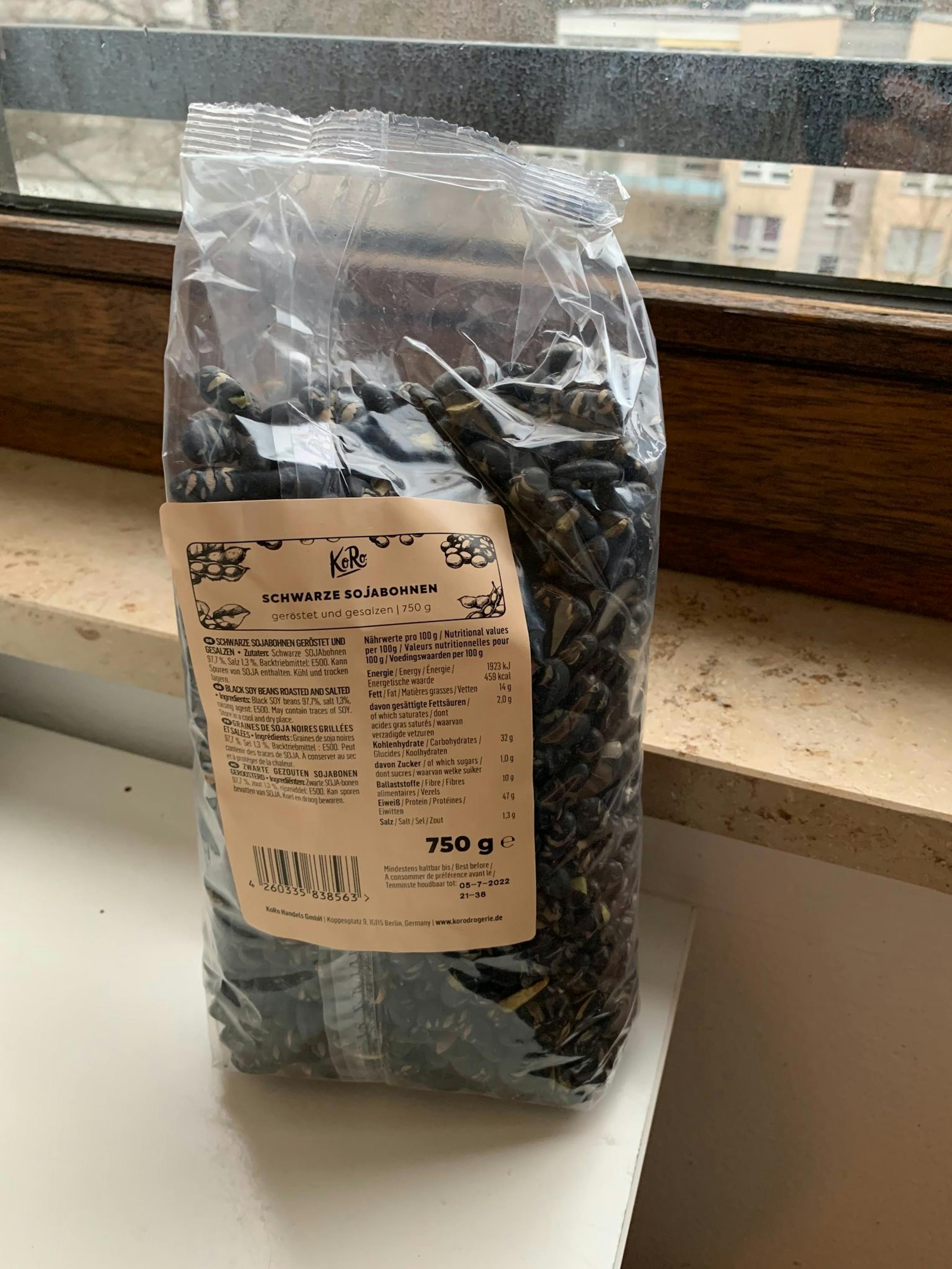 eine Tüte schwarze Sonnenblumensamen steht auf einem Fensterbrett