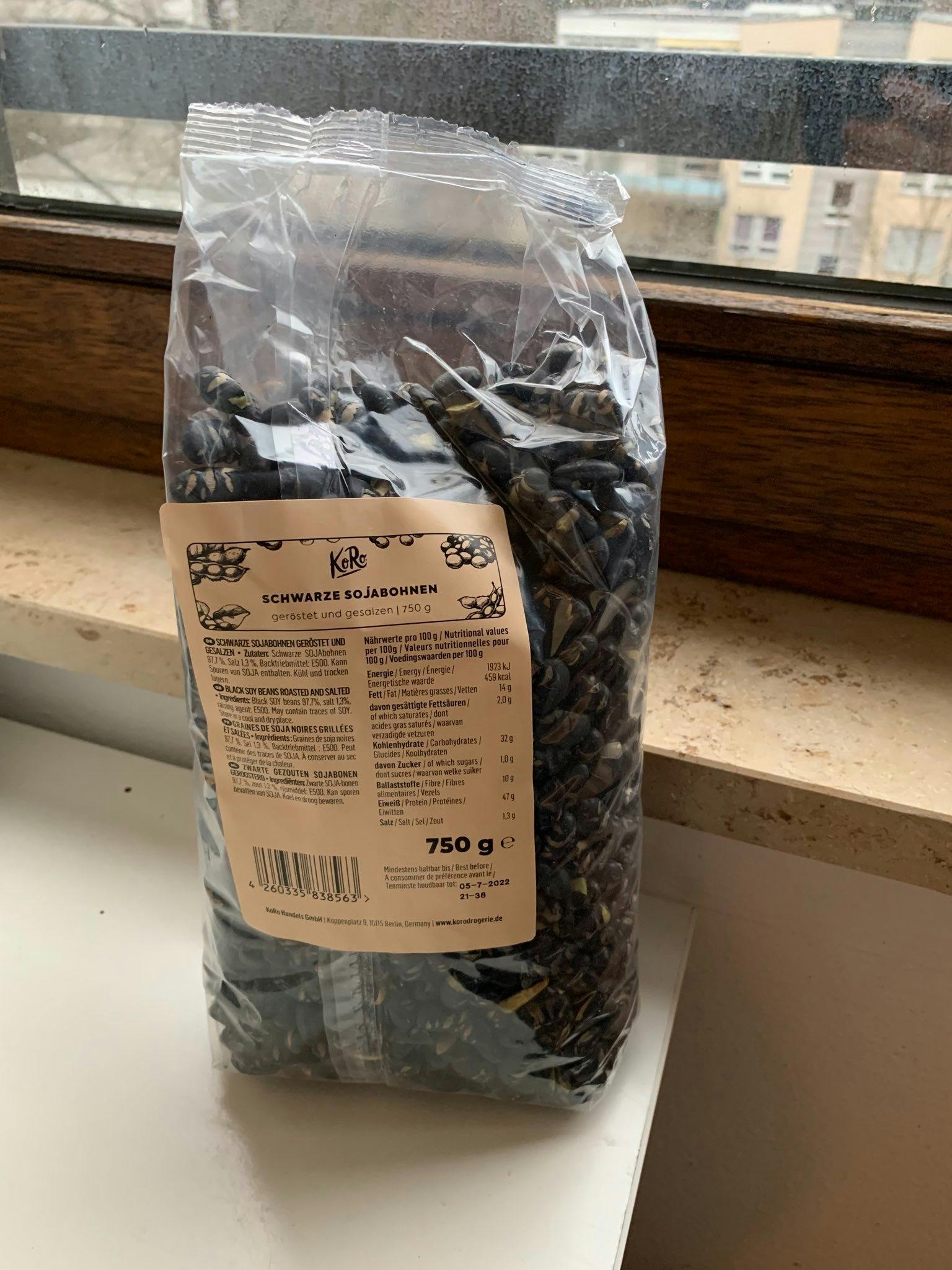 eine Tüte schwarze Sonnenblumensamen steht auf einem Fensterbrett