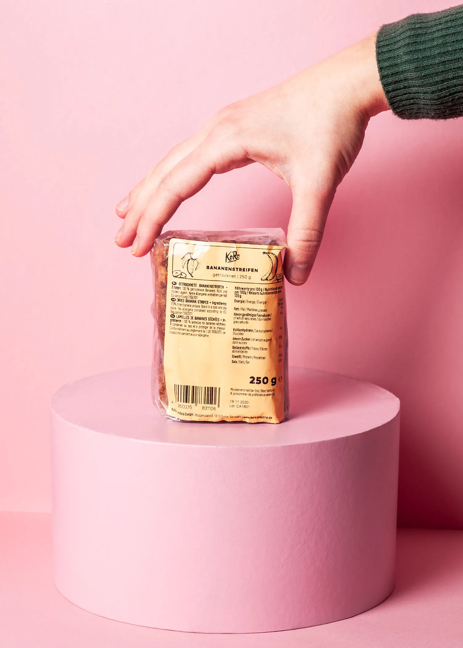 une personne tient une boîte de biscuits à la banane sur un support rose