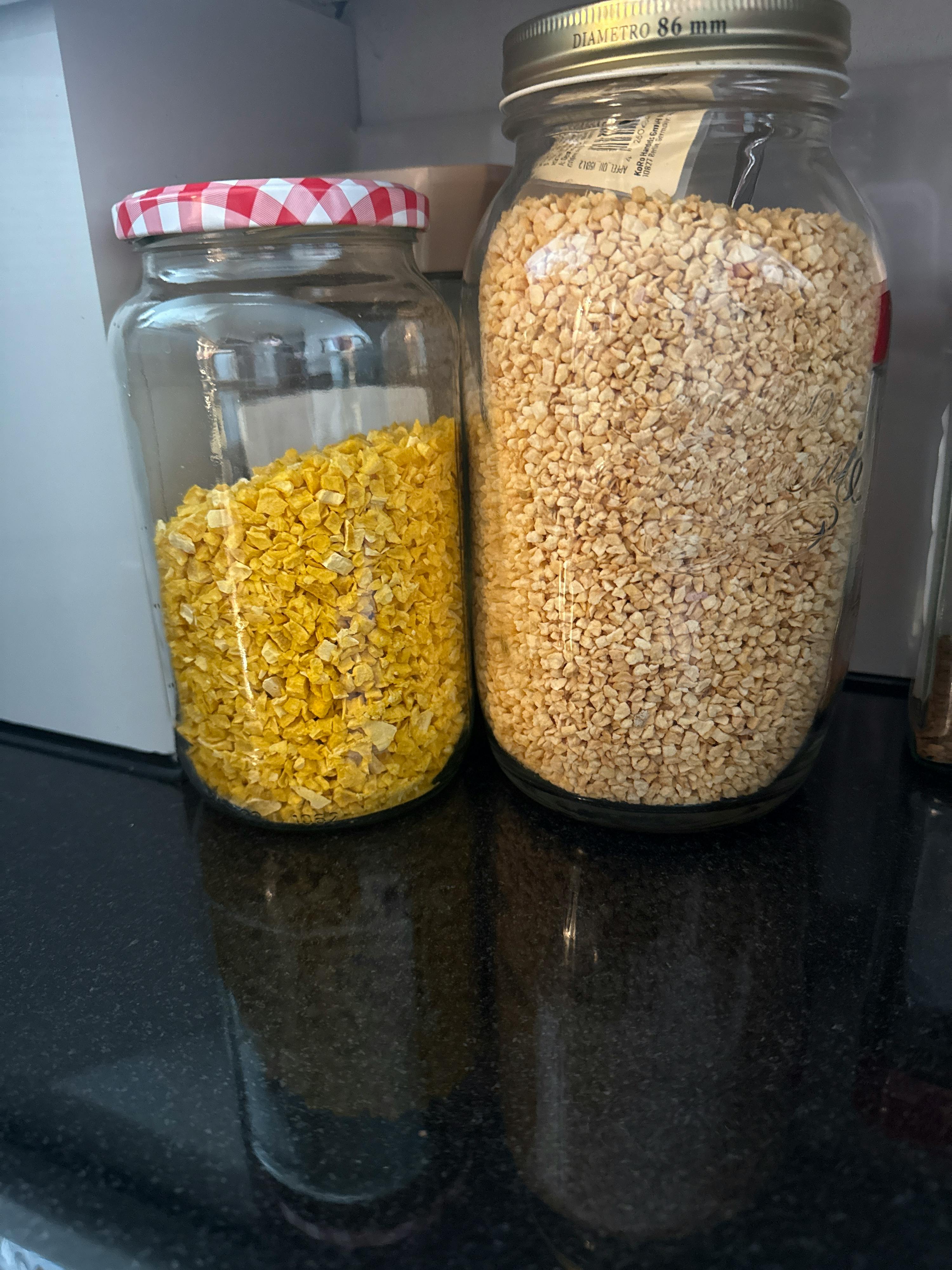 zwei liegende gläser, gefüllt mit hellen und gelben körnigen lebensmitteln.