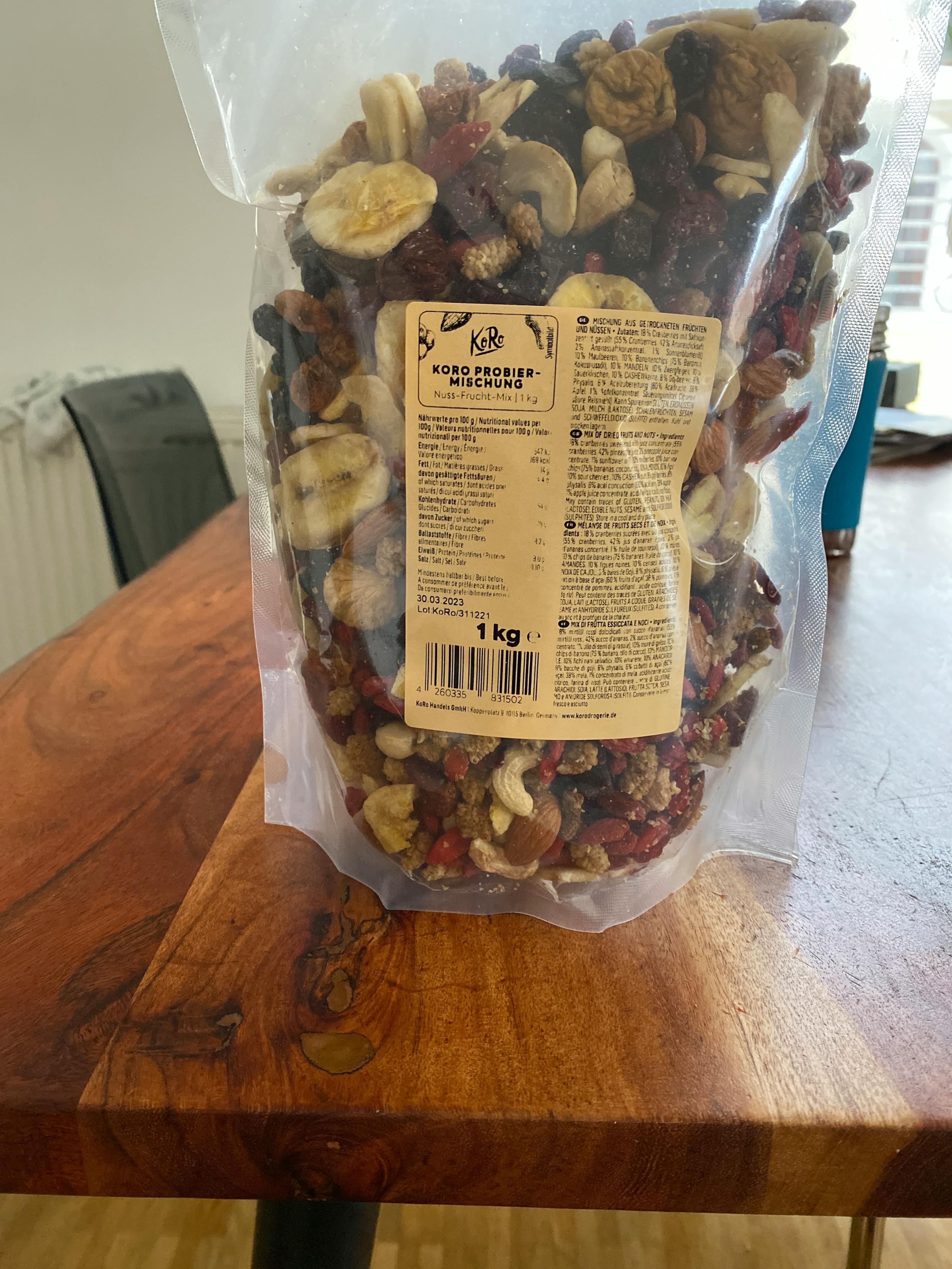 ein Plastikbeutel mit trockenfrüchten und Nüssen steht auf einem Holztisch