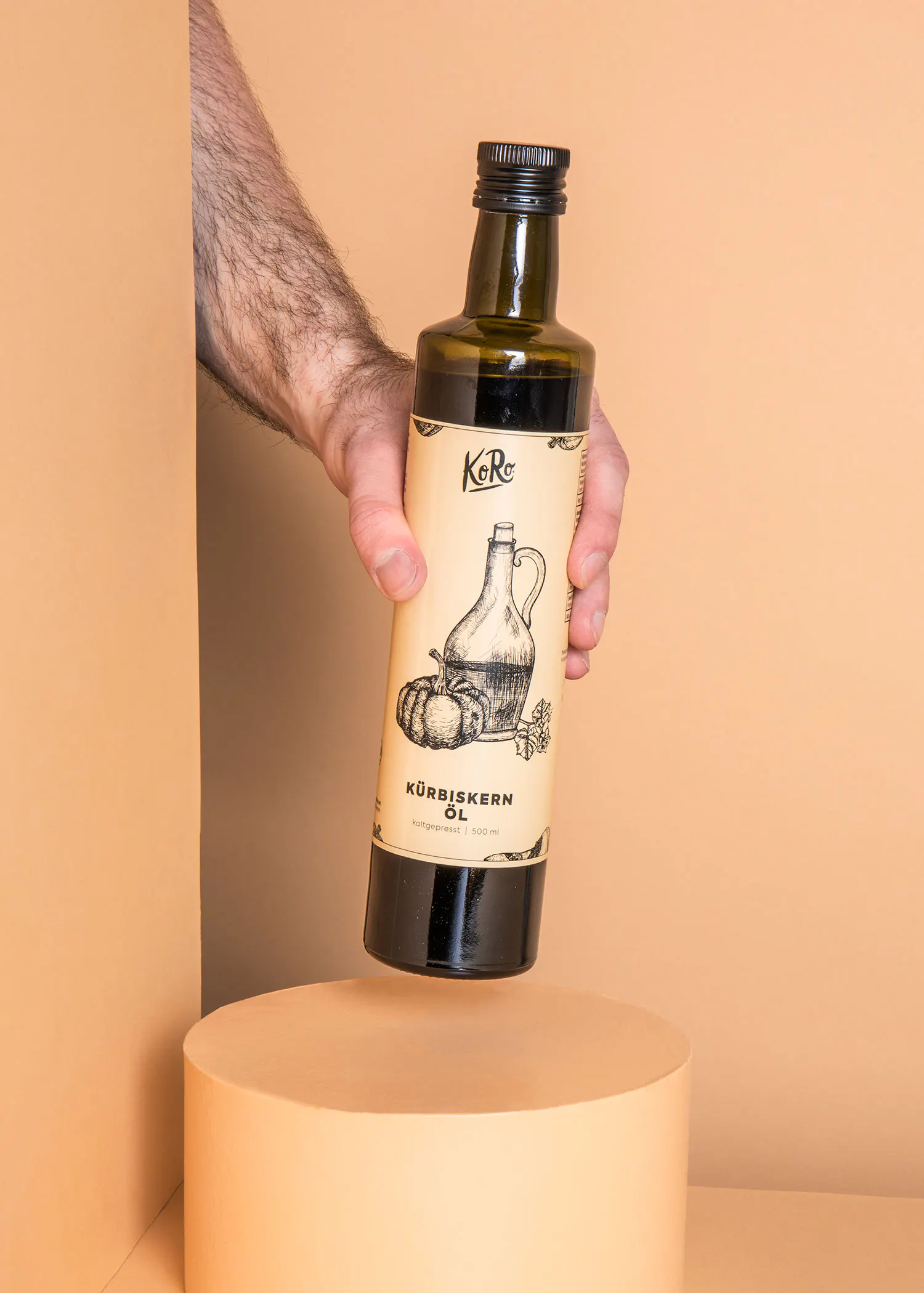a hand is holding a bottle of kurbiskern oil