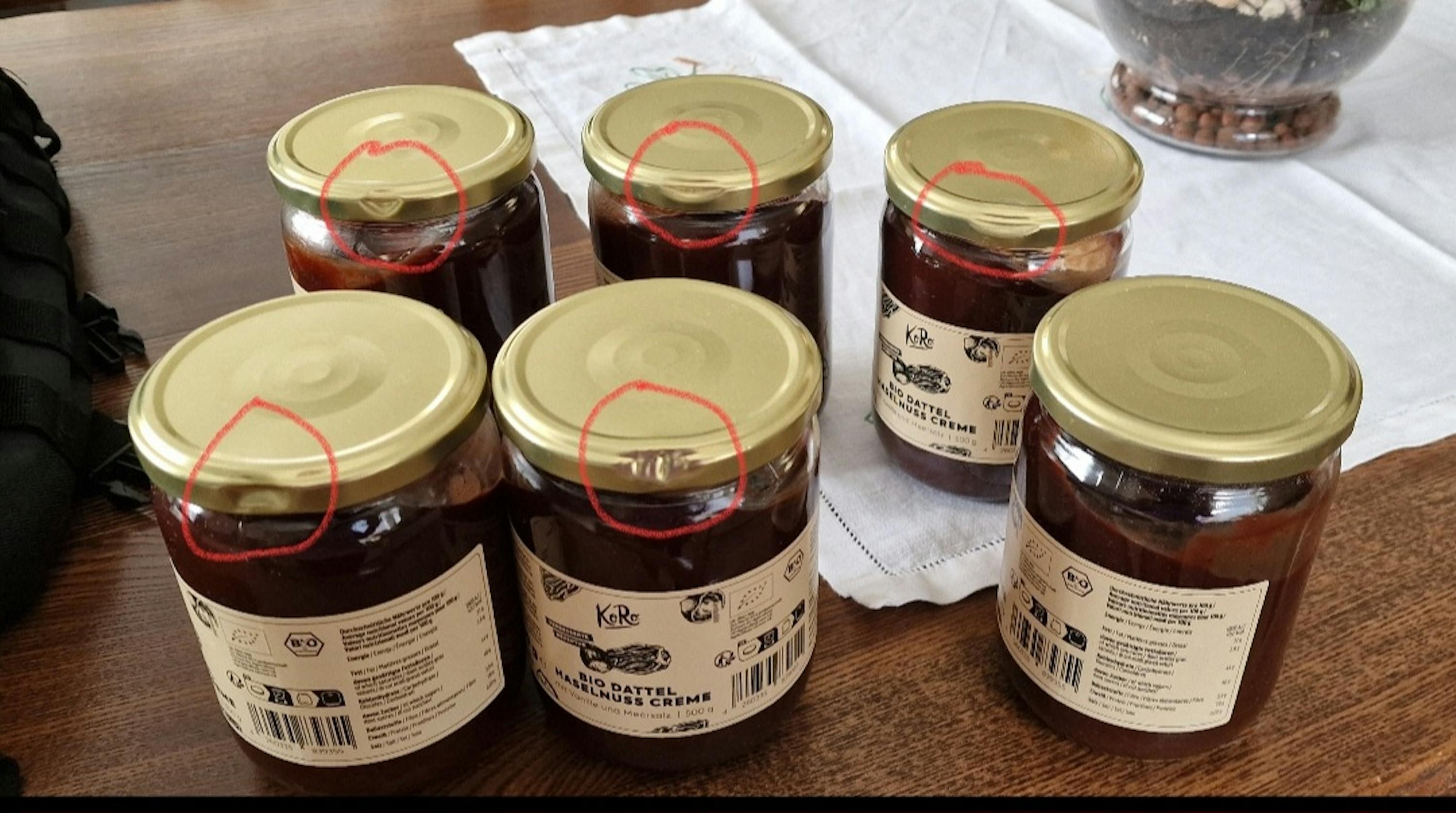 six bocaux de confiture sont assis sur une table