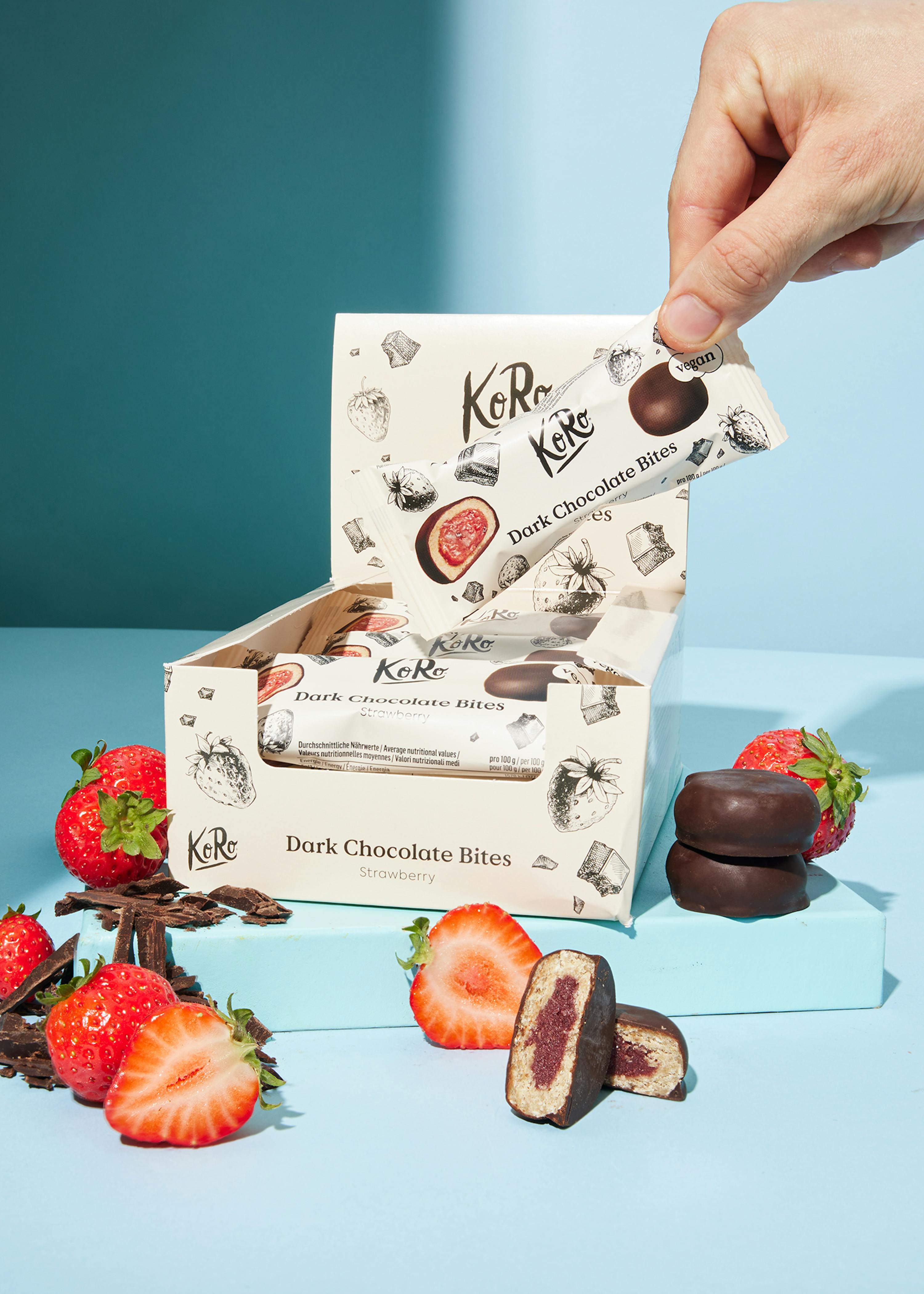 une boîte de biscuits au chocolat noir avec des fraises à côté