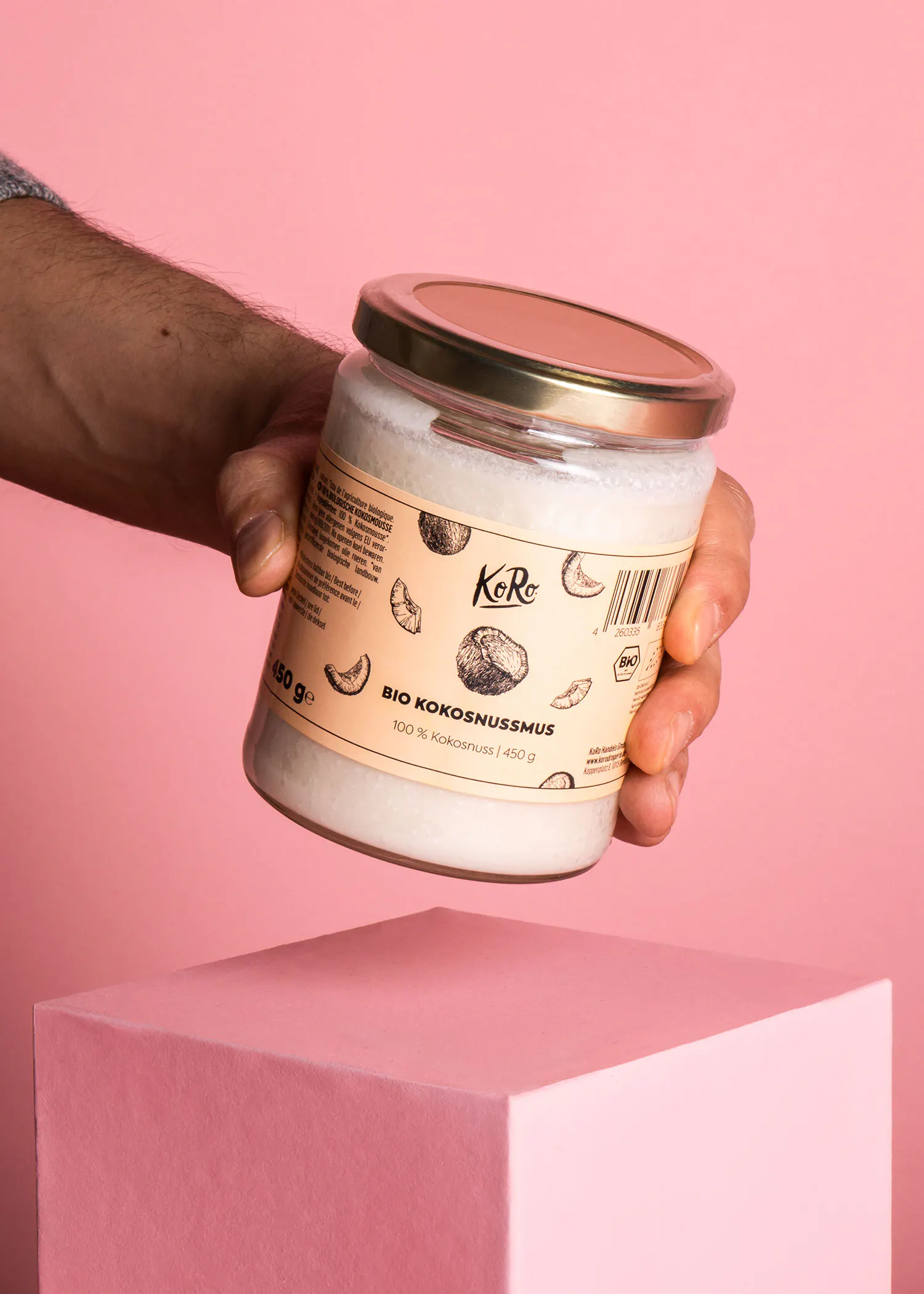 une personne tient un bocal d' huile de coco bio