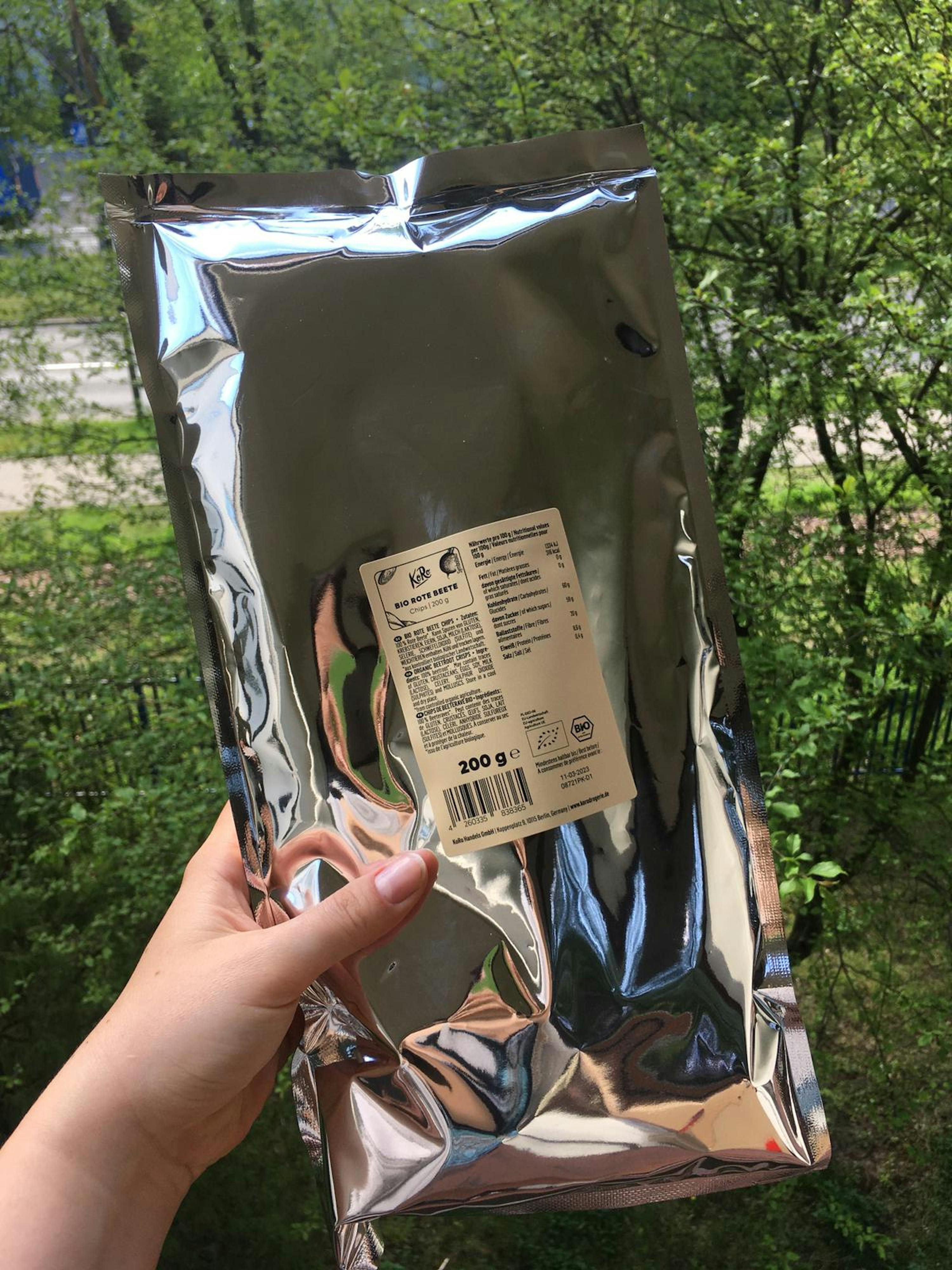 eine Person hält einen silbernen Plastikbeutel mit einem weißen Etikett darauf