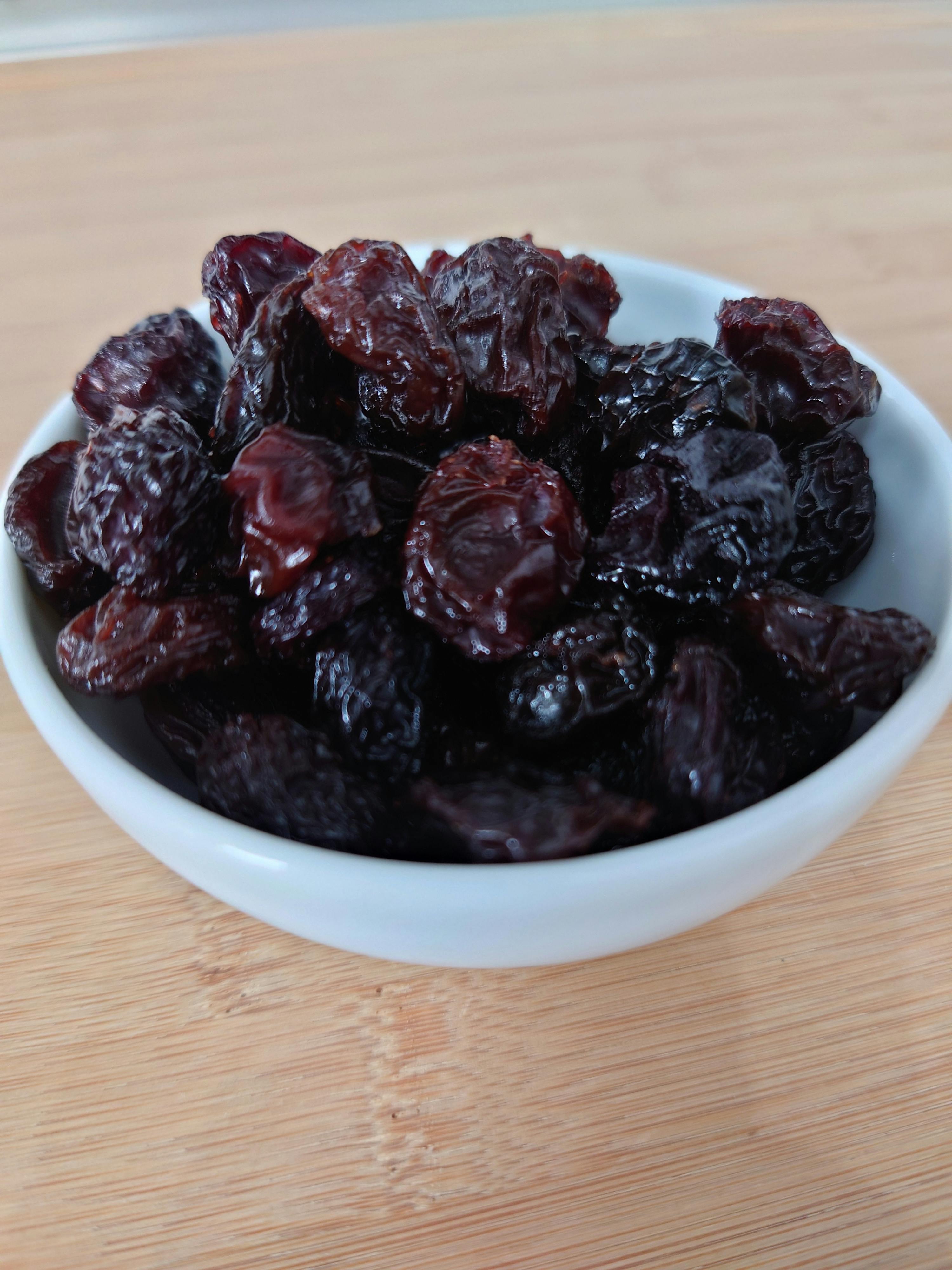eine weiße Schüssel mit Kirschen auf einem Holztisch