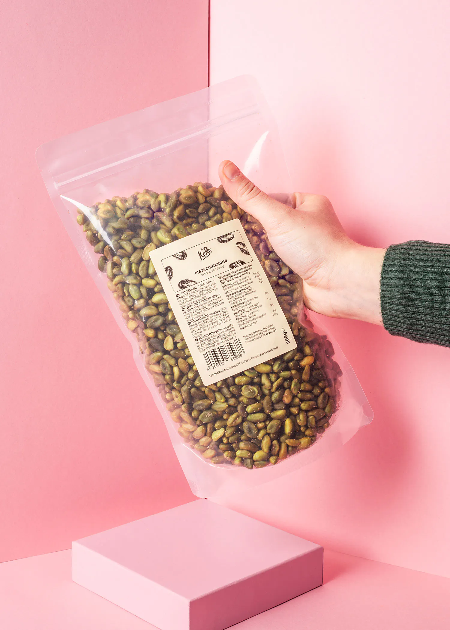 une personne tient un sac de pistaches sur un fond rose