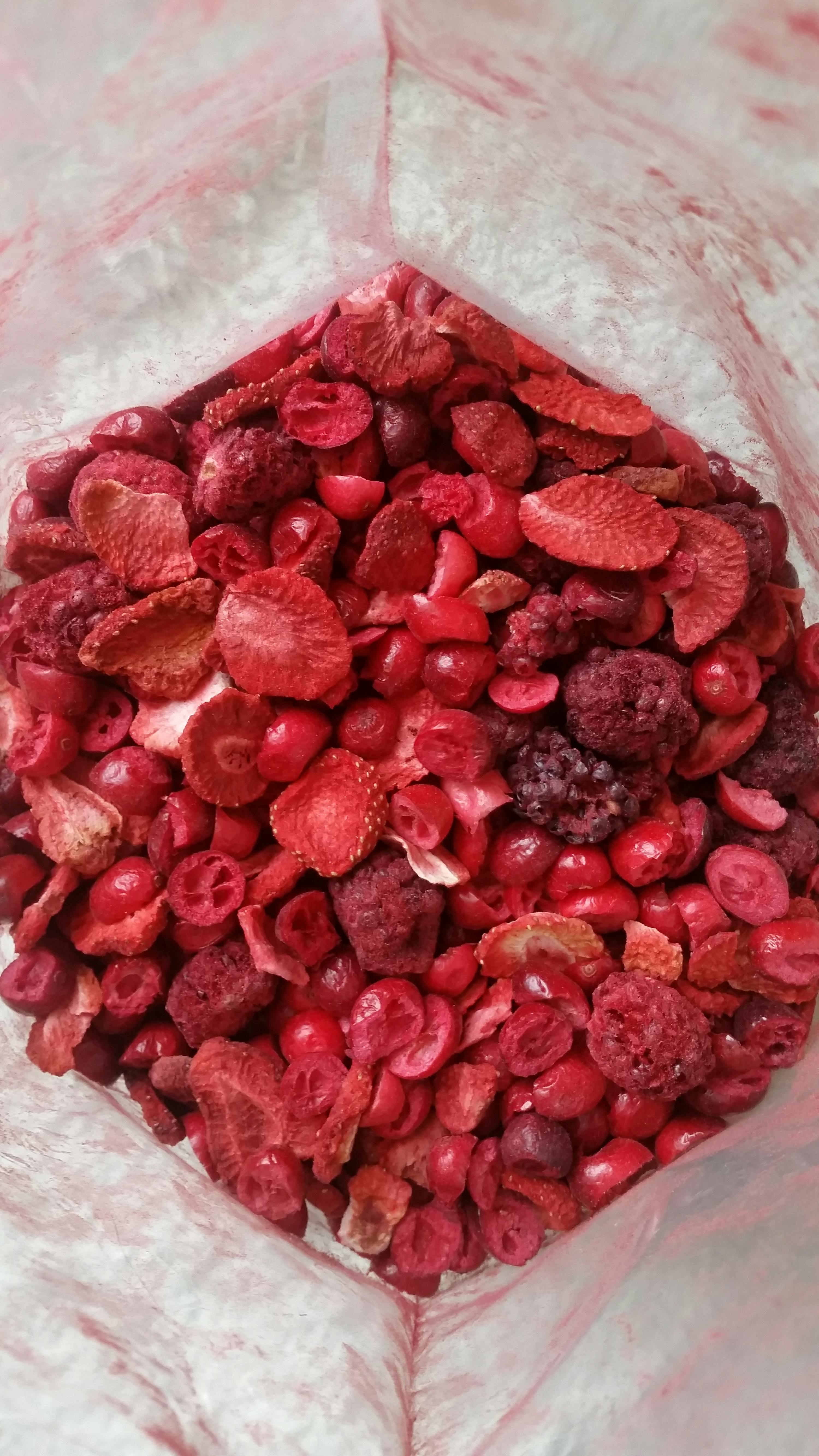 a bag filled with red berries including strawberries raspberries and cherries