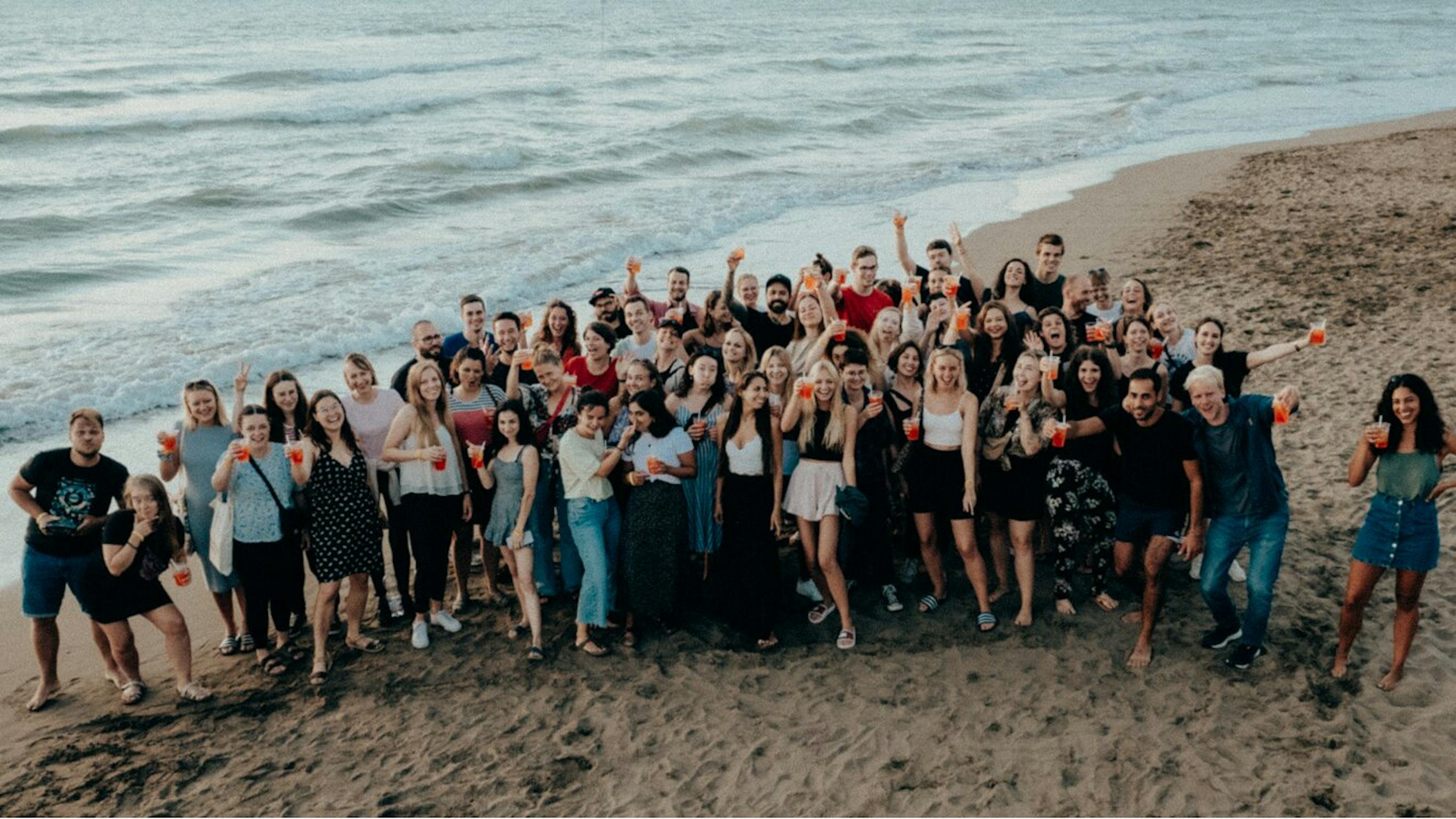 a large group of people are posing for a picture on the beach