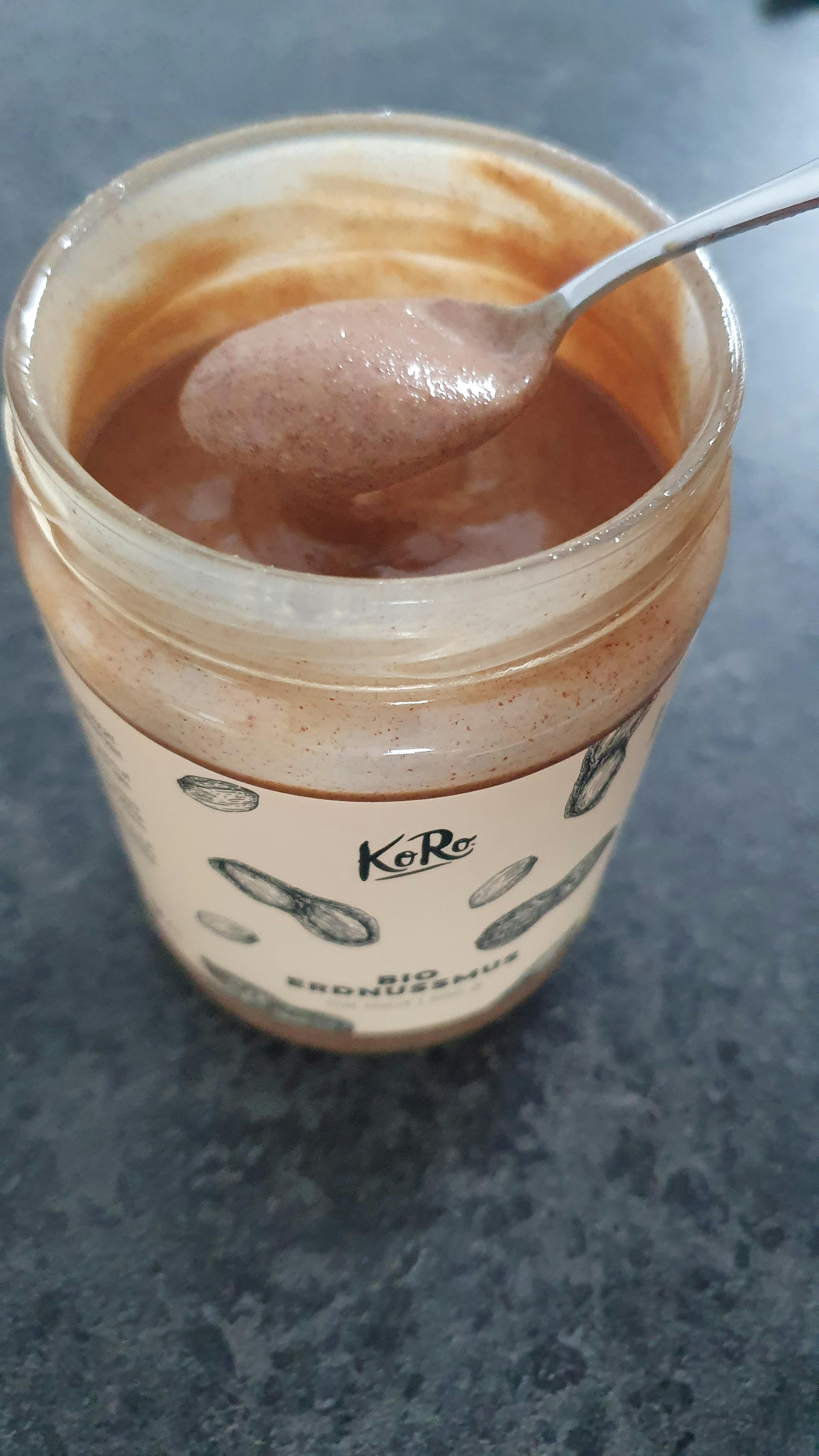 un gros plan d' un bocal de beurre de cacahuète avec une cuillère à l' intérieur