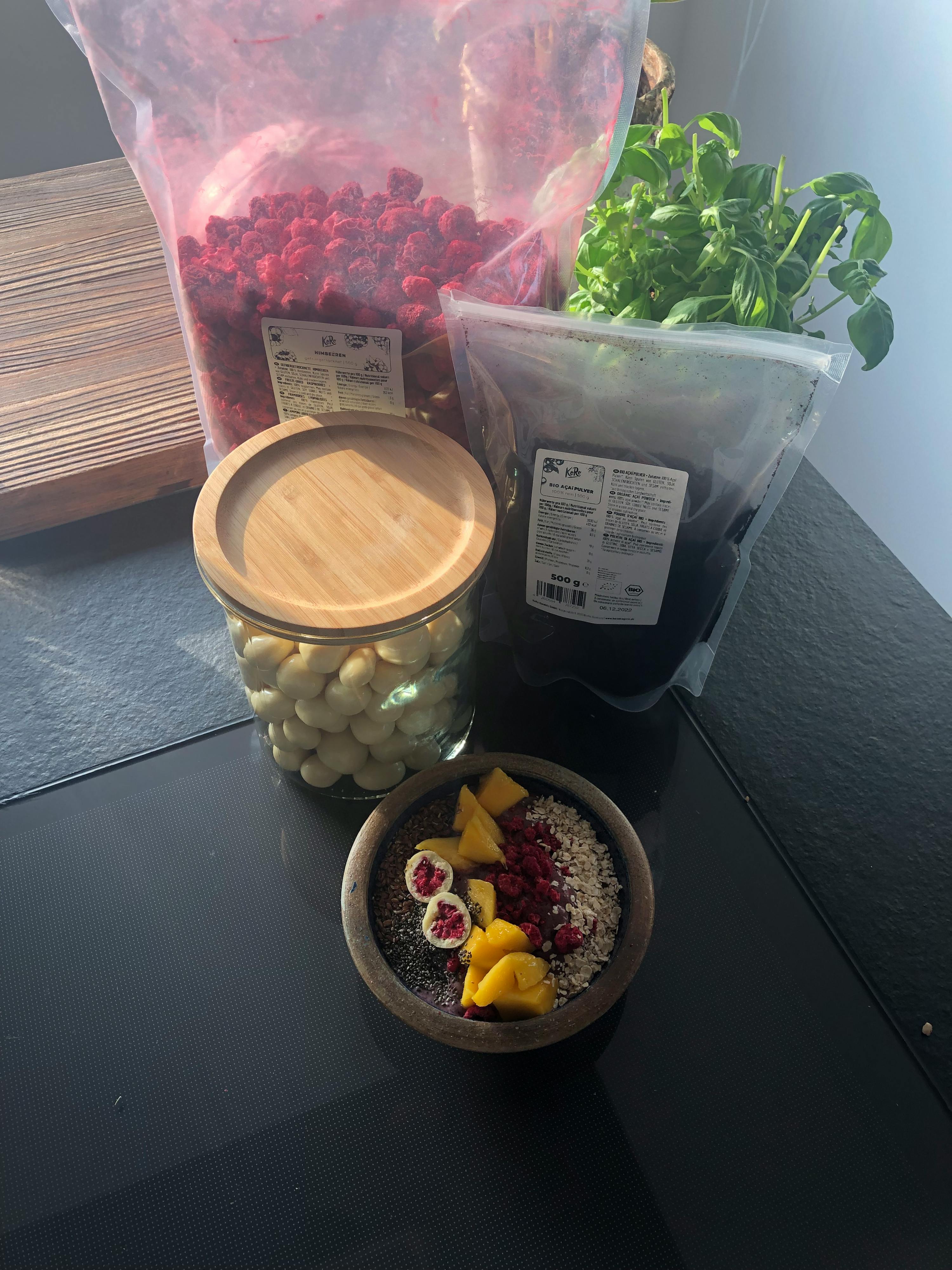 a bag of dried raspberries sits next to a bowl of fruit