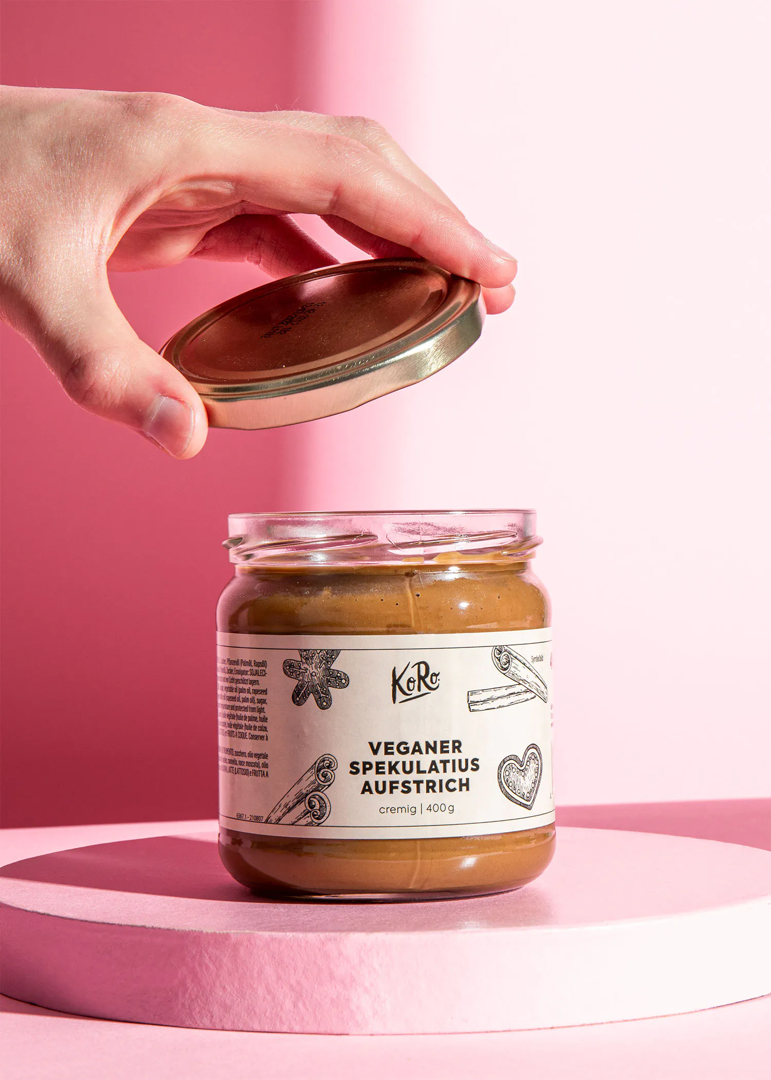 une personne tient le couvercle d' un bocal en verre avec une étiquette blanche qui dit " veganer speculatius aufstrich "