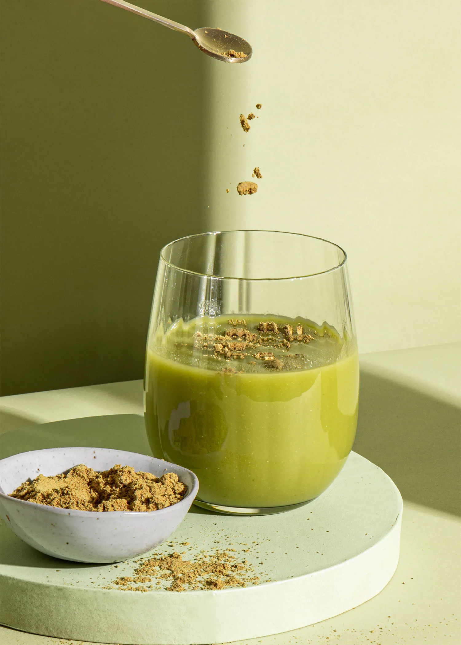 un verre de soupe verte avec une cuillère dessus