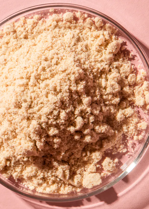 un bol en verre rempli de poudre blanche sur fond rose