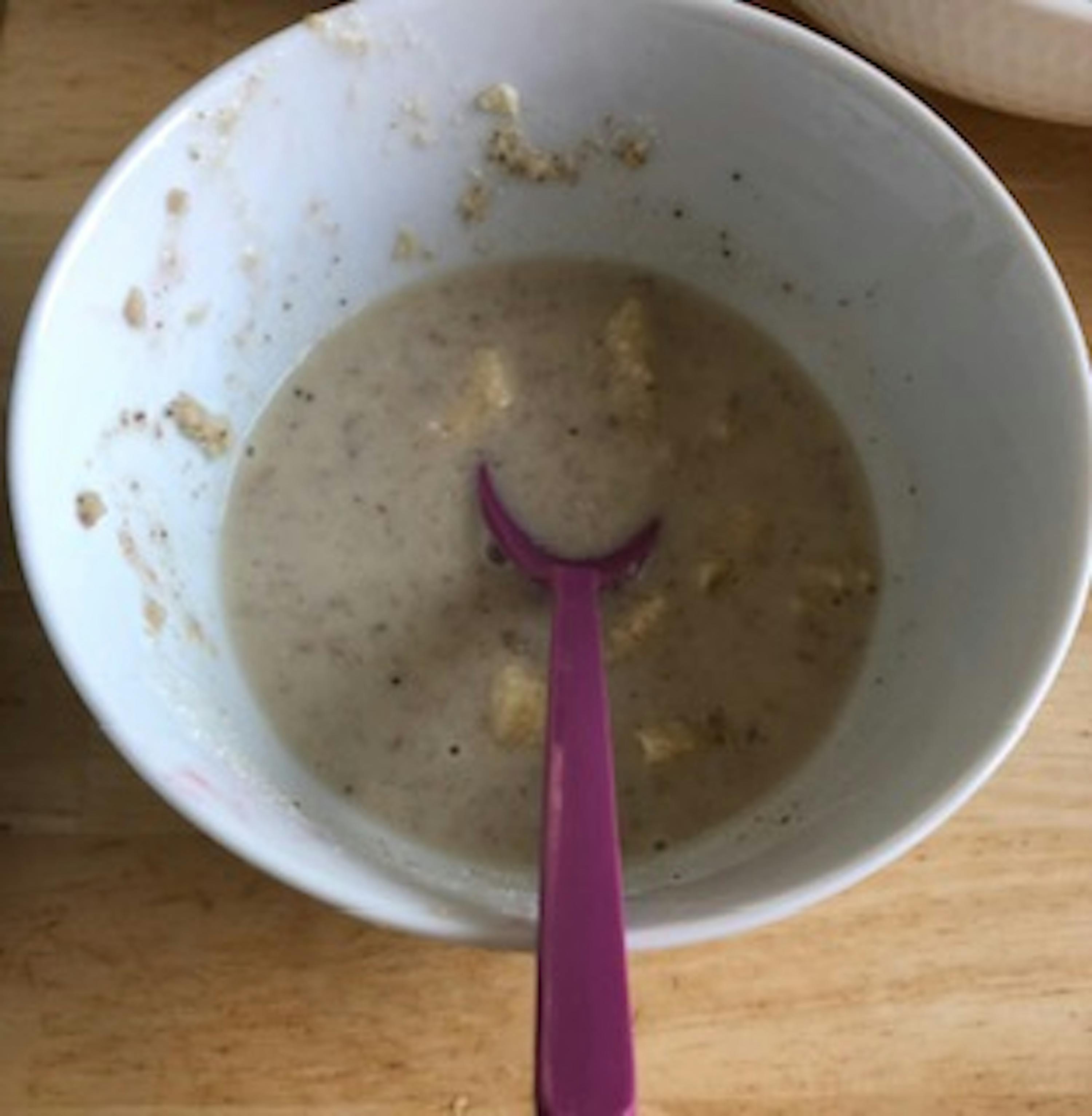 un bol blanc rempli de soupe avec une cuillère violette