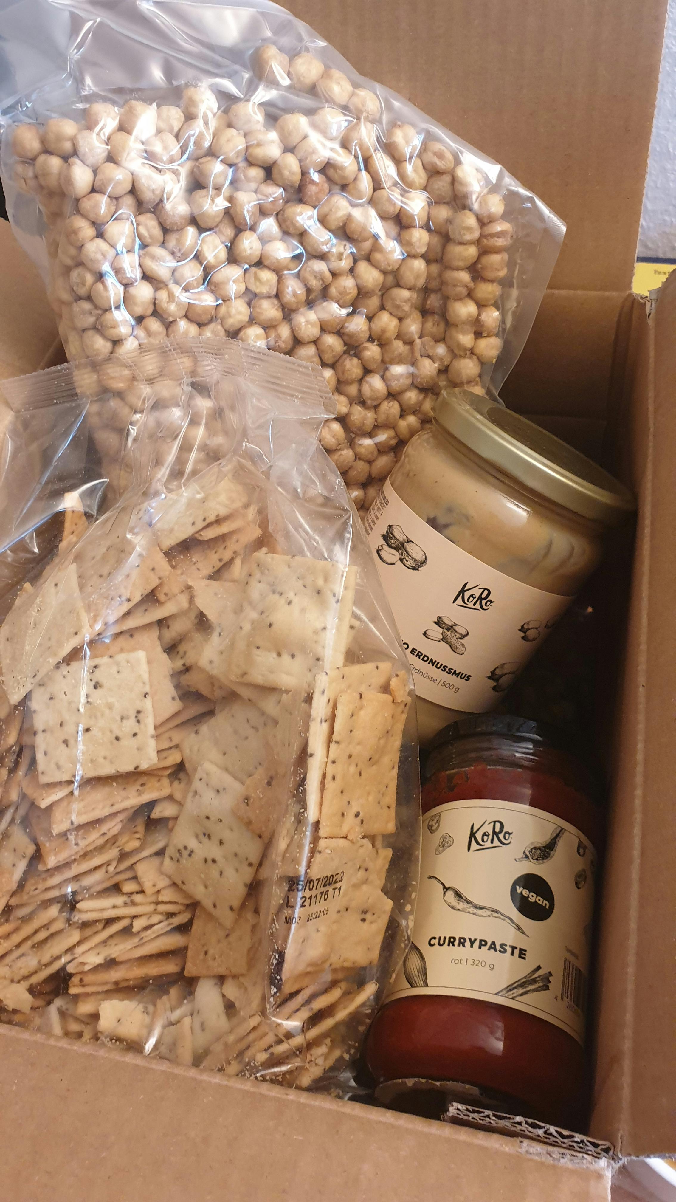 una scatola piena di crackers e ceci e un barattolo di curry paste