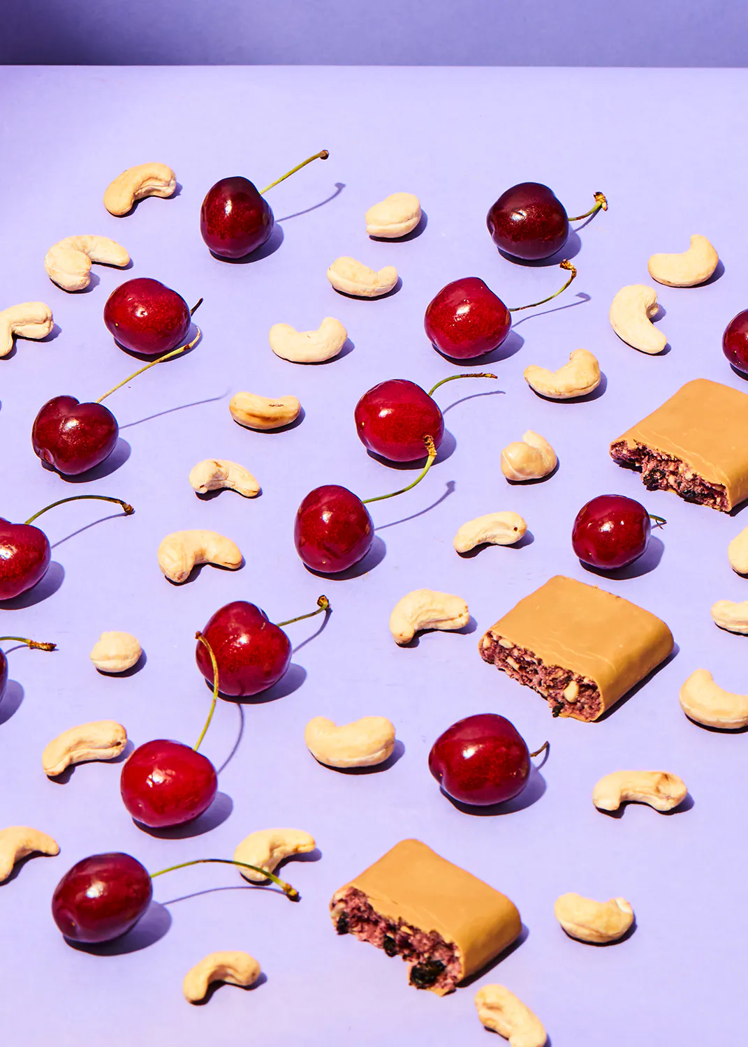 des cerises et des noix de cajou sur une surface violette