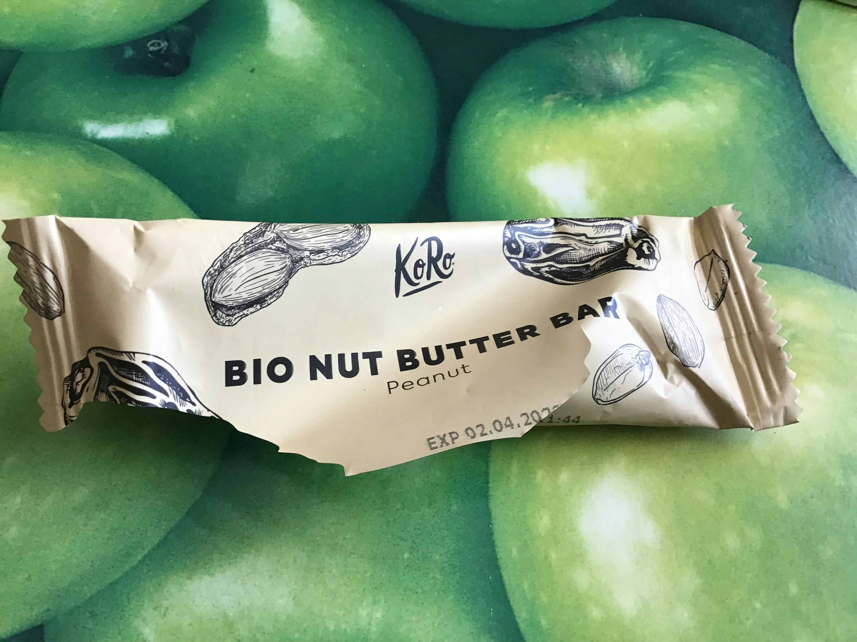 ein bio Erdnussbutter-Riegel liegt auf einem Tisch mit grünen Äpfeln