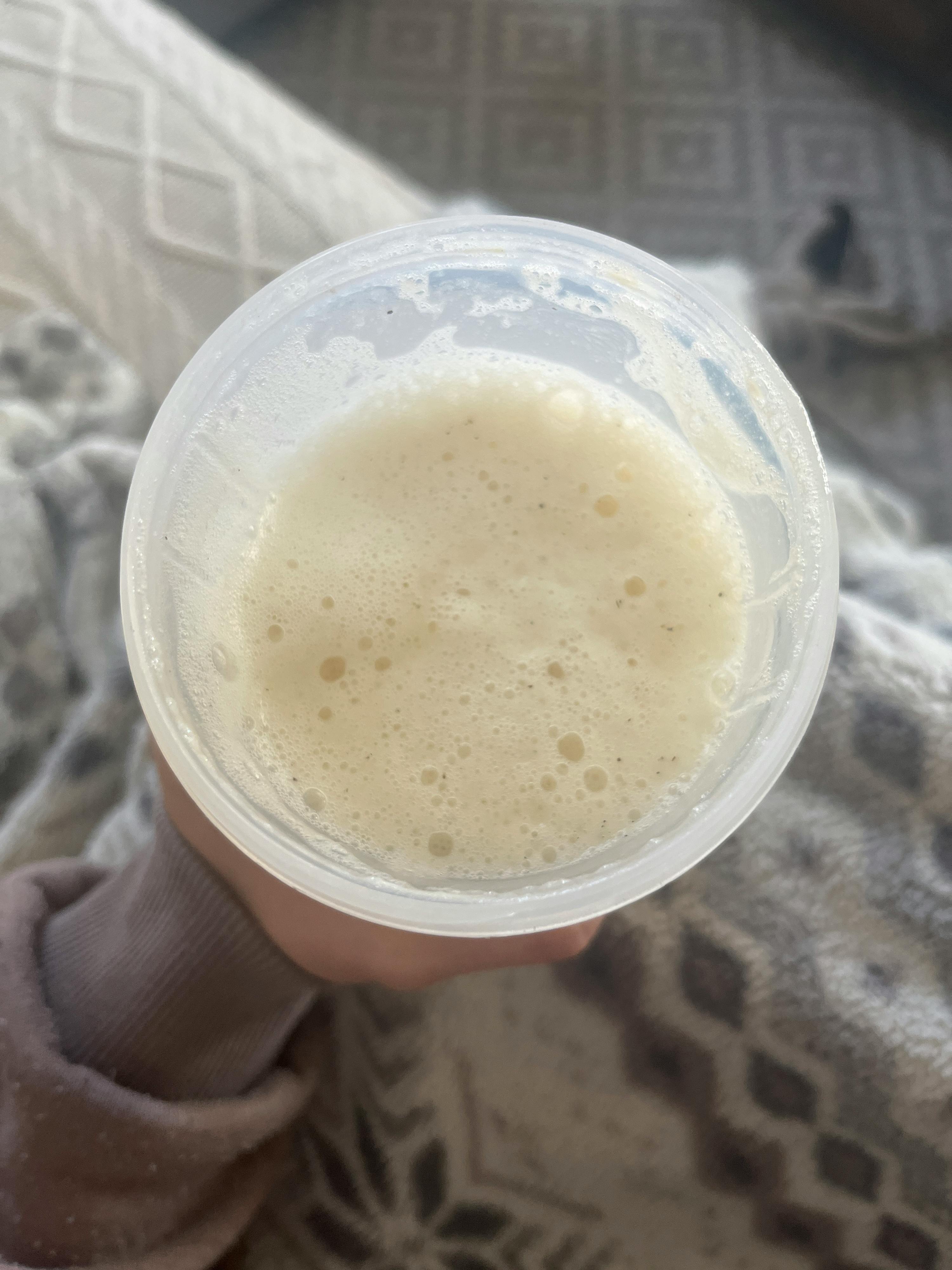 a person is holding a plastic cup with a white liquid in it