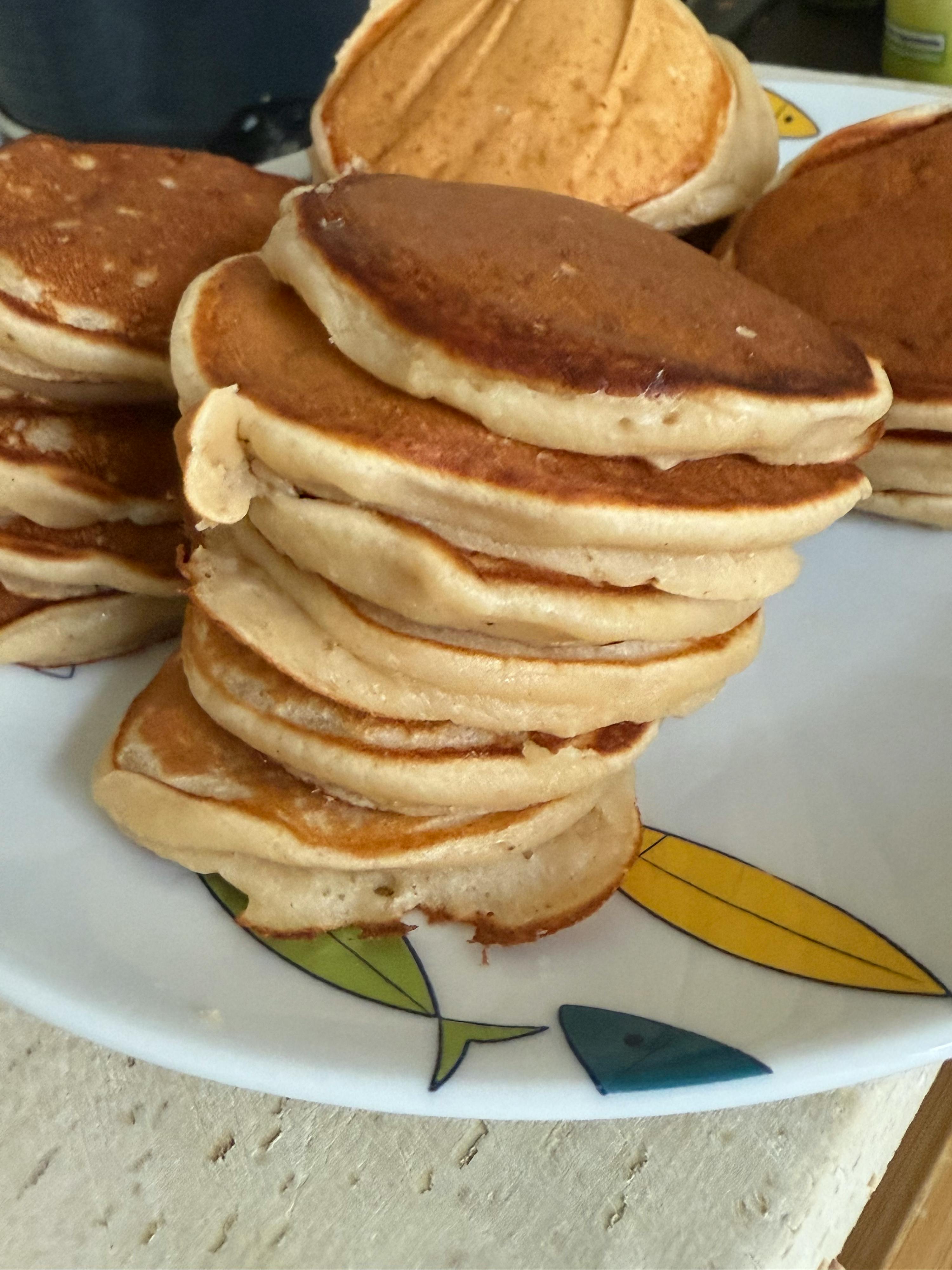 una pila di frittelle su un piatto bianco con foglie colorate