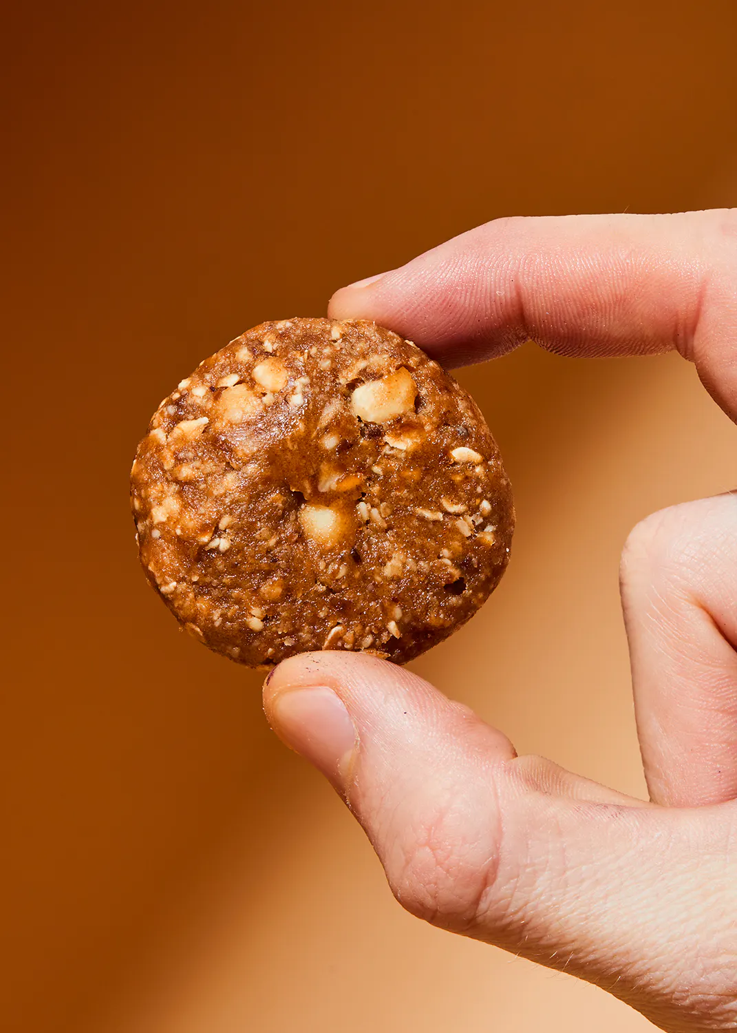 une main tient un biscuit avec des noix dessus