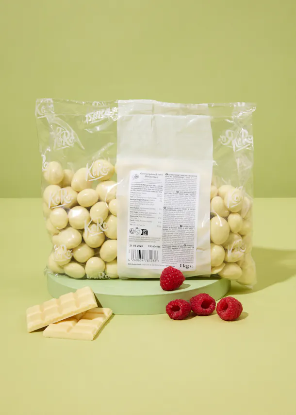 un sac de chocolat blanc est assis sur une table avec des framboises