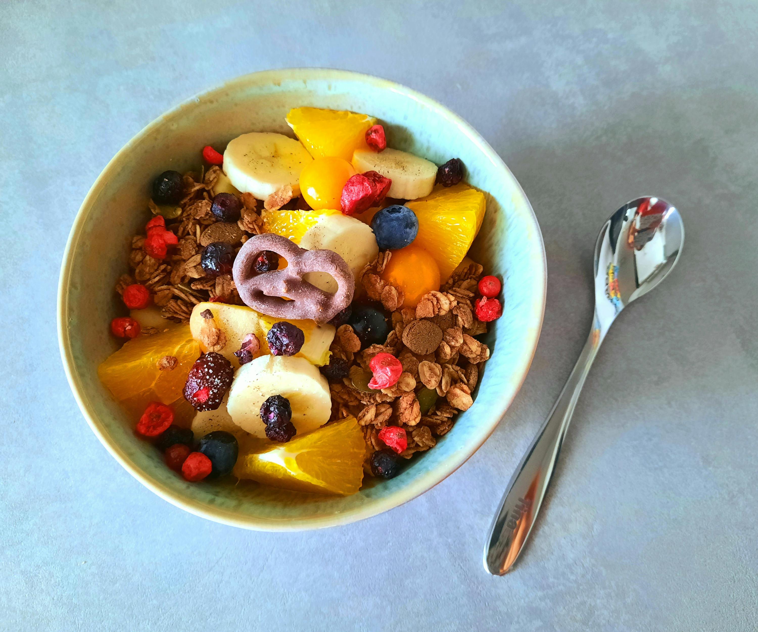 a bowl of granola and fruit next to a spoon