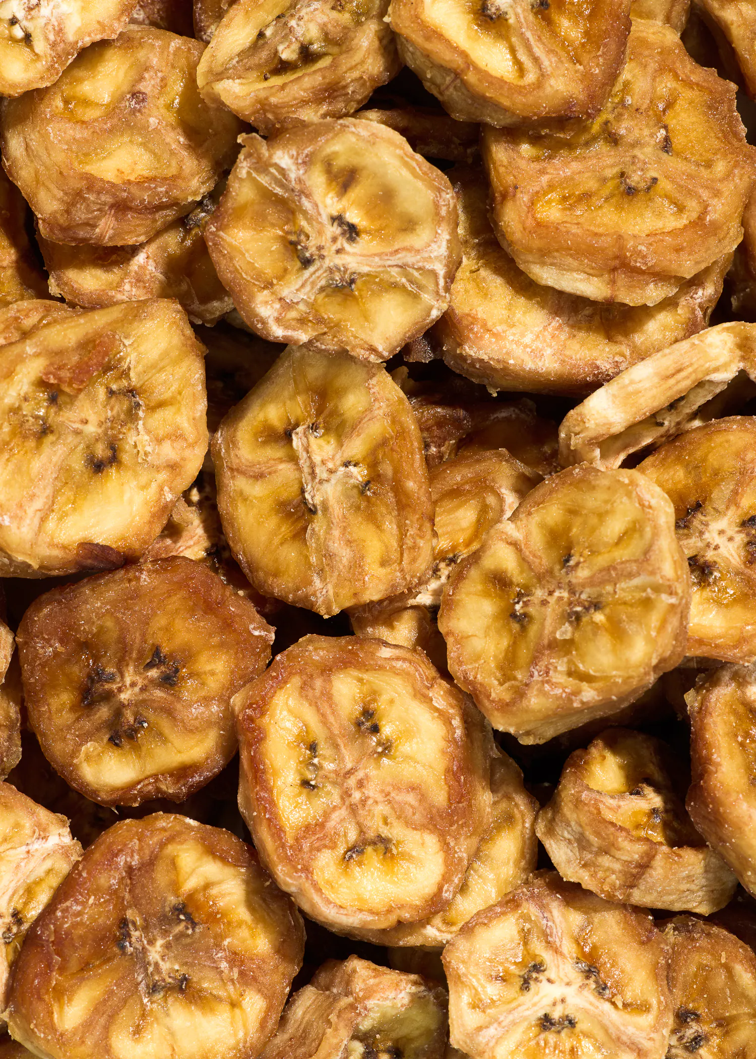 a pile of dried banana slices with a few black spots on them