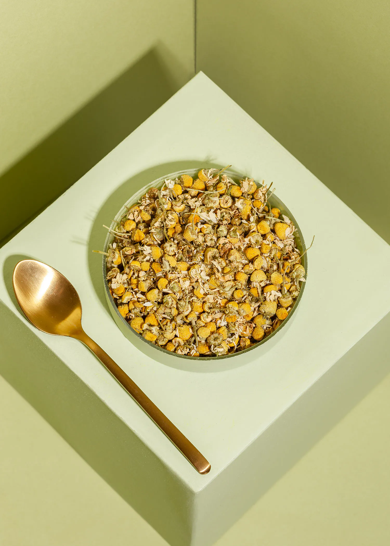 a bowl of dried flowers next to a spoon