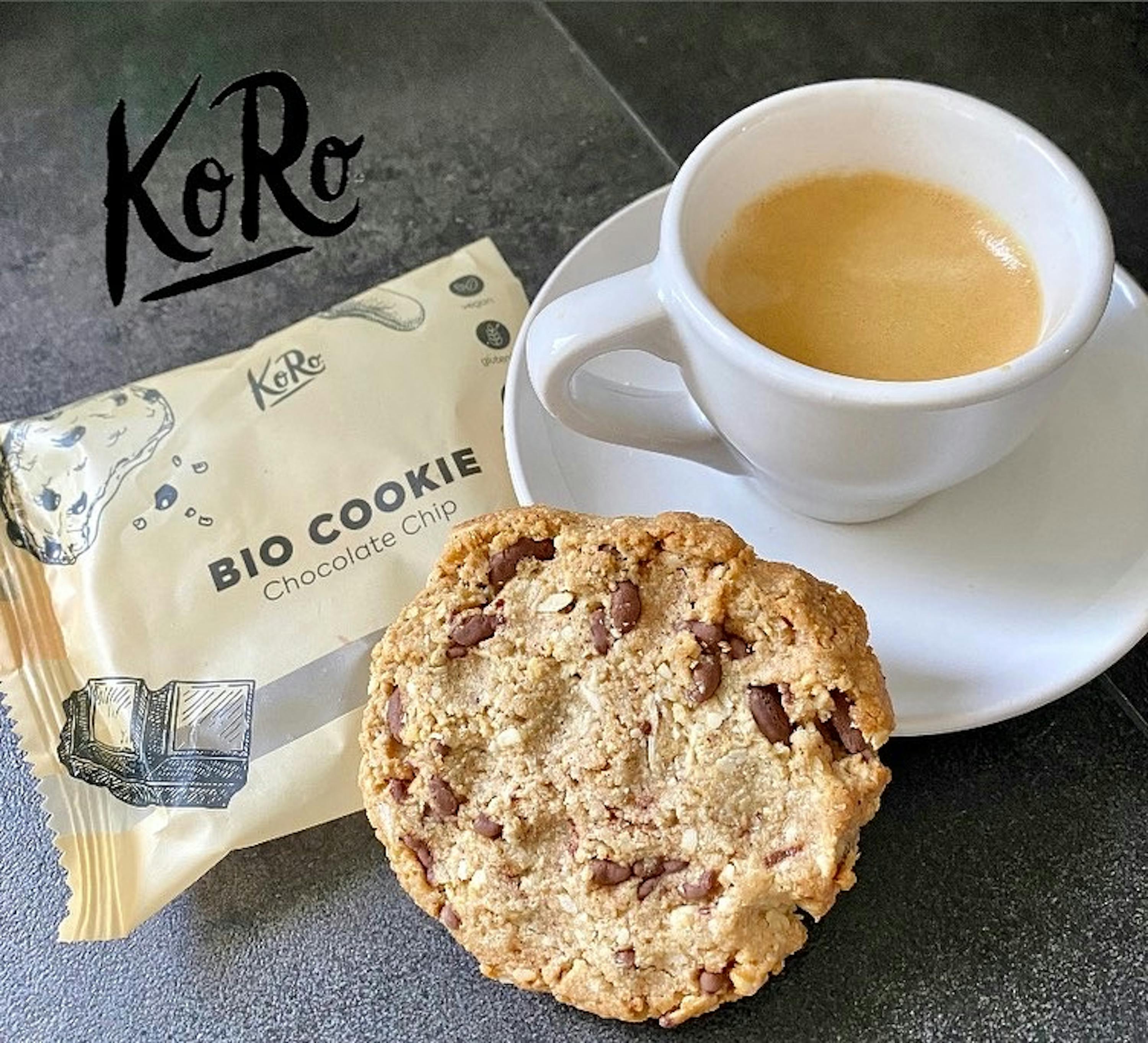 ein Bio-Keks mit Schokoladenstückchen sitzt neben einer Tasse Kaffee