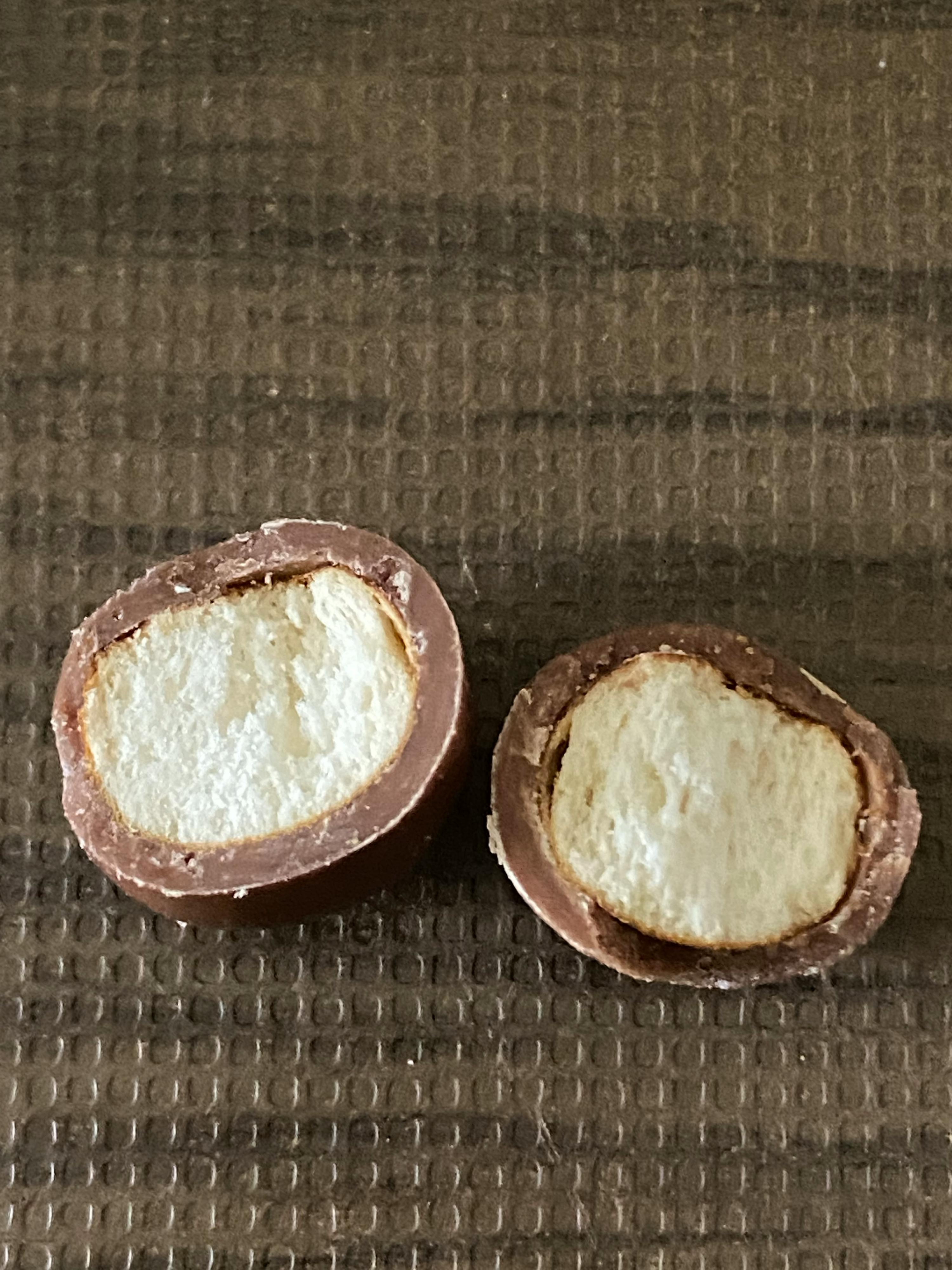 two chocolate eggs are cut in half on a gray surface
