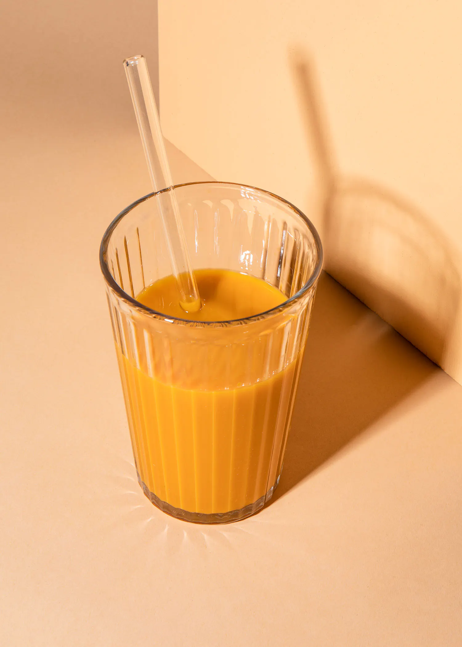 un verre rempli d' un liquide orange et d' une paille