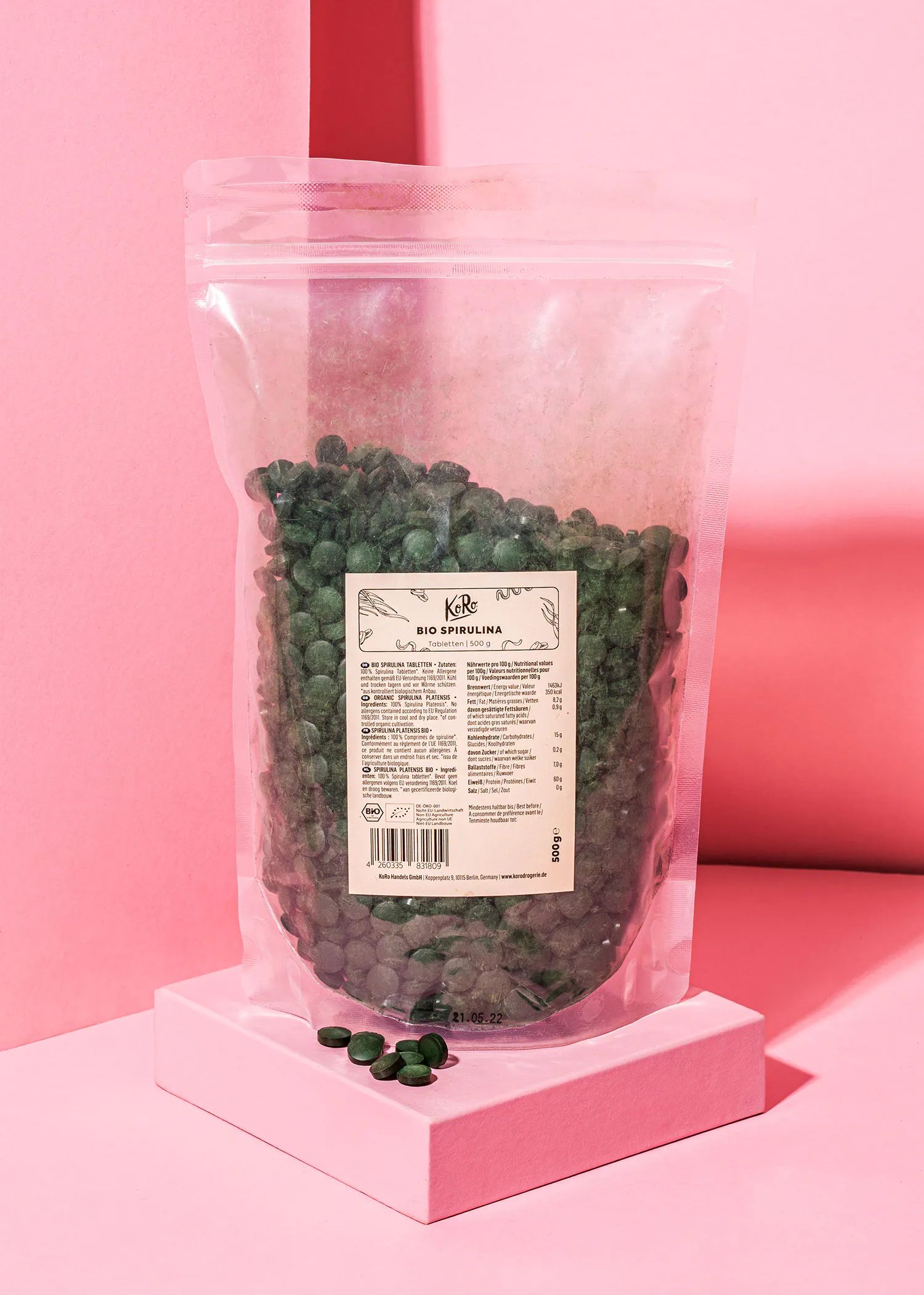 un sac de spirulina bio est posé sur une surface rose